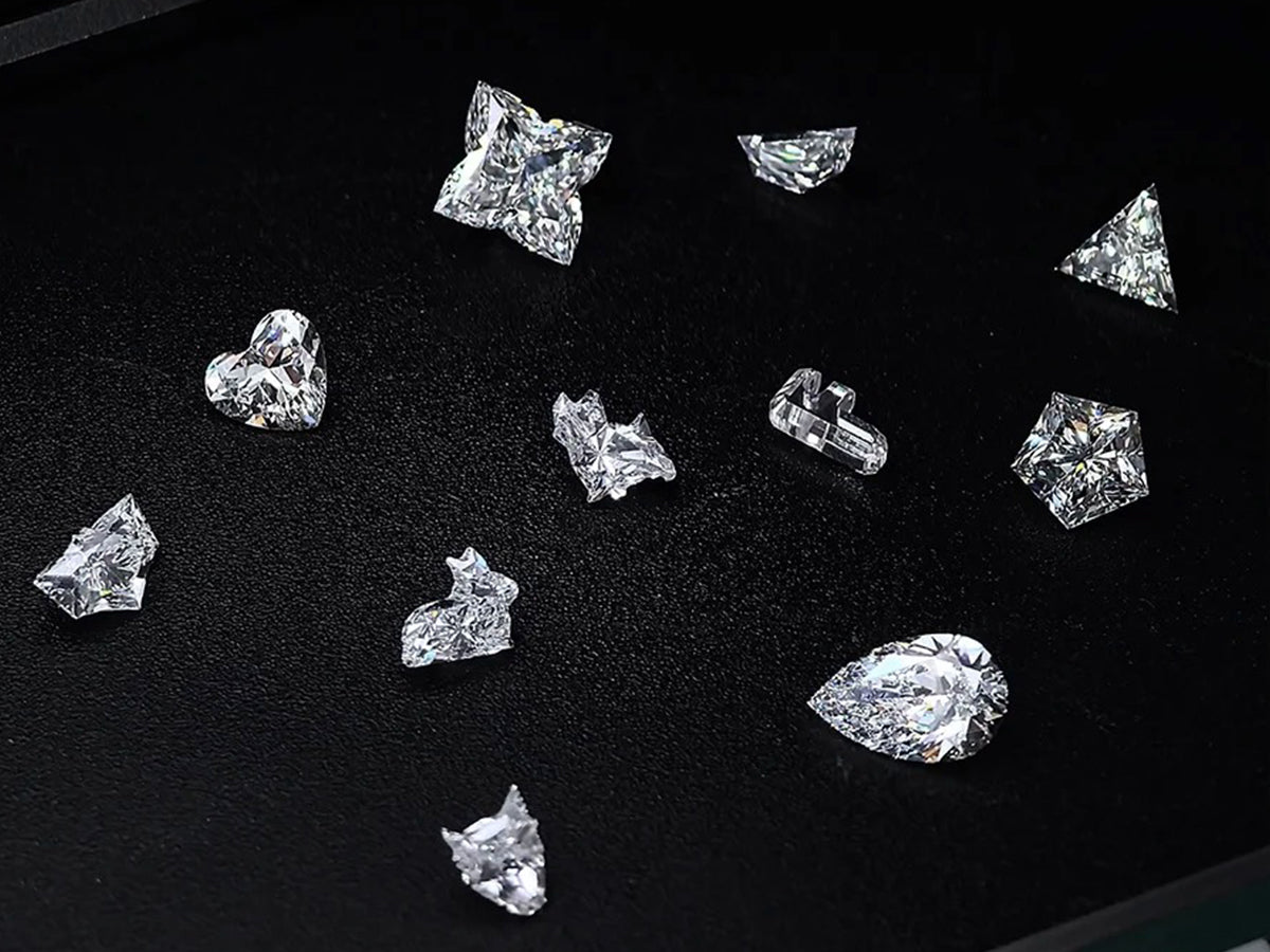 Various diamond shapes, including heart, triangle, pear, and more, arranged on a black background, highlighting their unique cuts