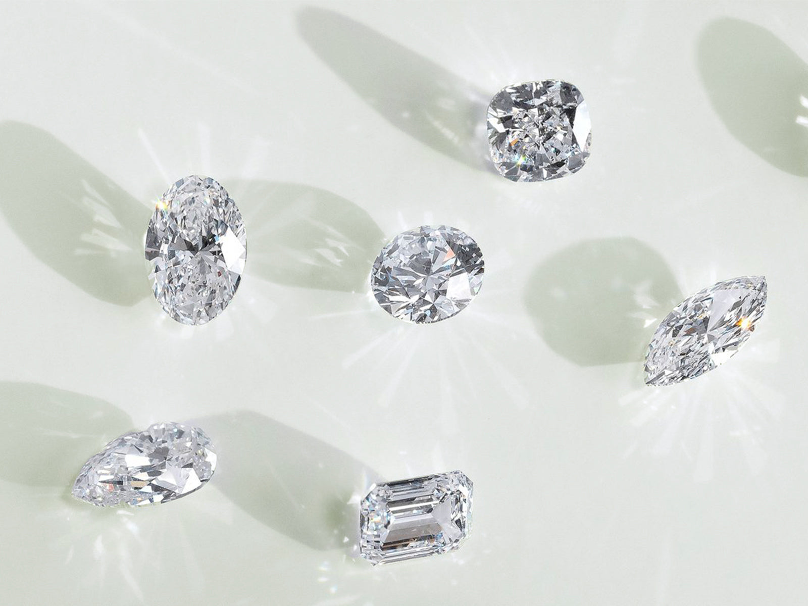 Stunning lab grown jewelry showcasing various diamond cuts—cushion, oval, pear, marquise, and emerald—displayed on a light background, ideal for eco-friendly jewelry designs