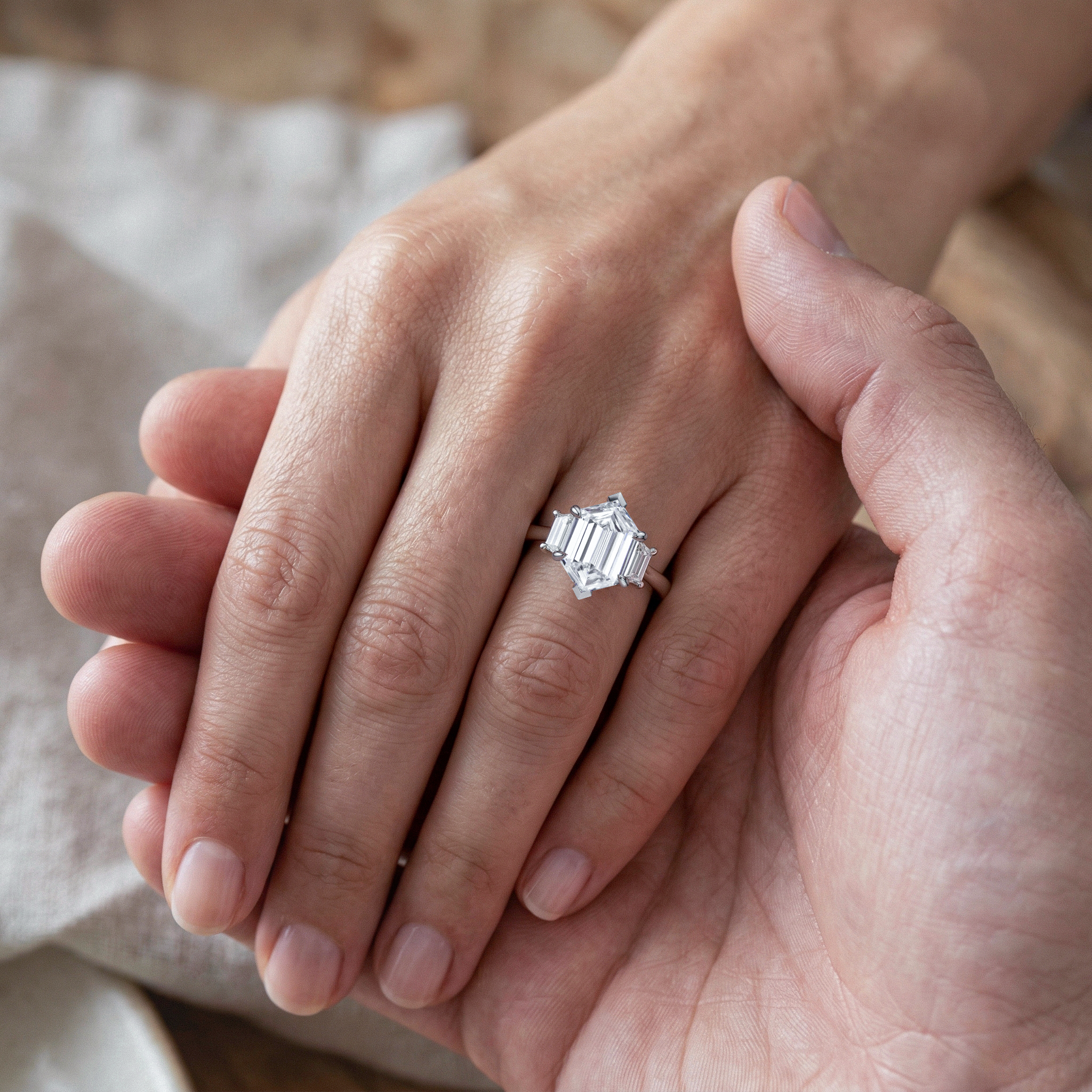 Close-up of hands holding each other with a hexagon lab diamond ring on one finger