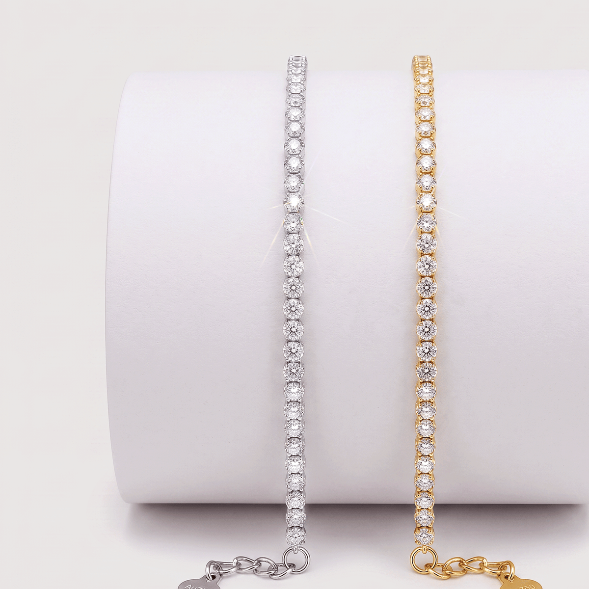 White and yellow gold lab-grown diamond tennis bracelets displayed side by side on a white jewelry stand.