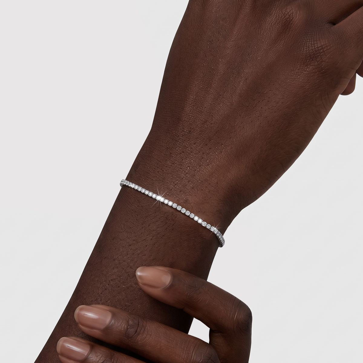 Model wearing a white gold lab-grown diamond tennis bracelet on the wrist.