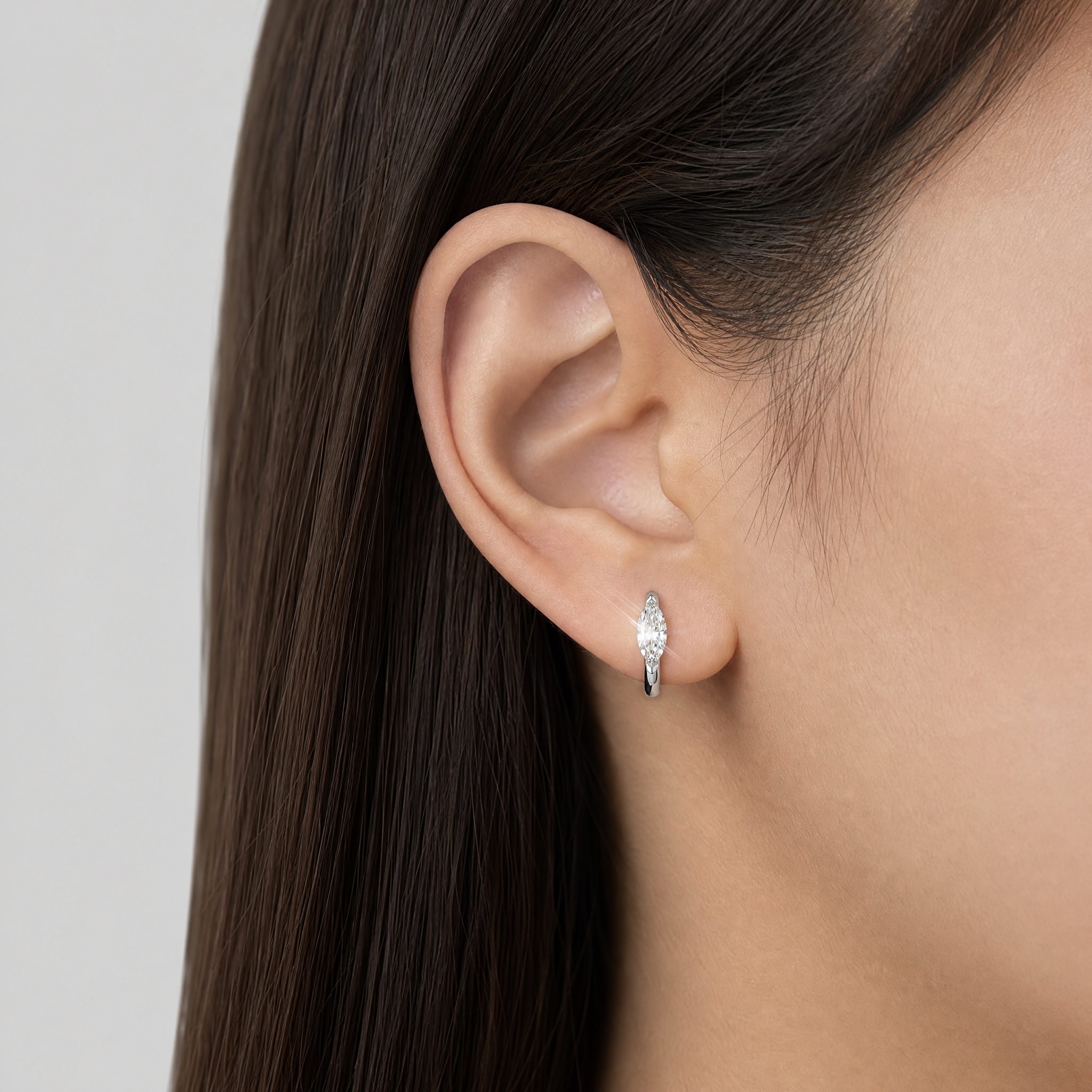 White-gold marquise-shaped hoop earring worn on an ear in a close-up model view.