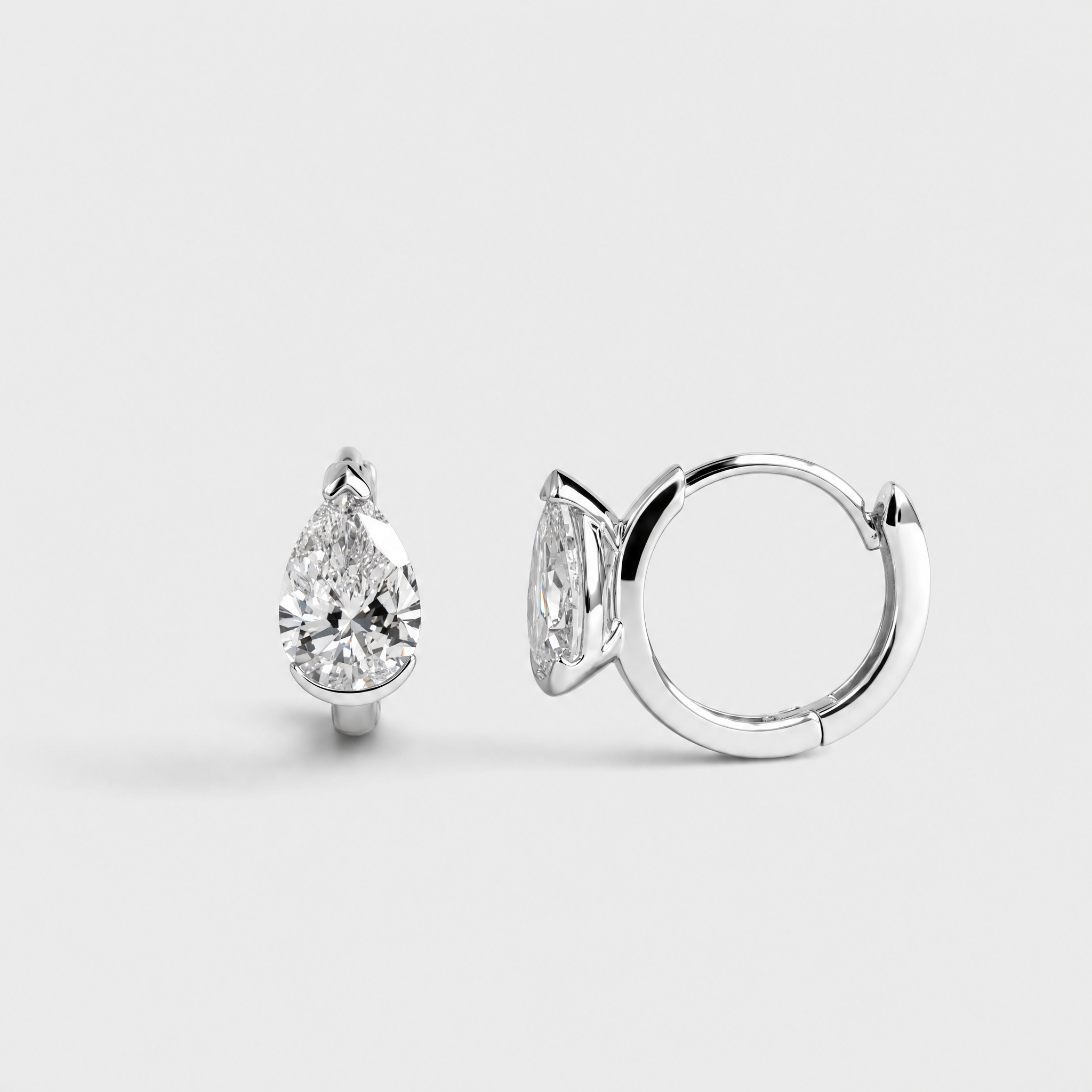 Rear profile view of pear-shaped hoop earrings in white gold showing the hoop closures and stone settings.
