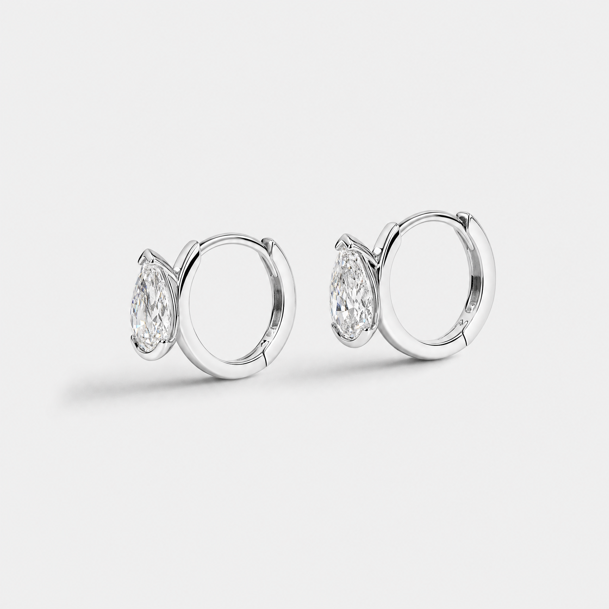 Side view of pear-shaped hoop earrings in white gold showing the hinged hoops and stone settings.