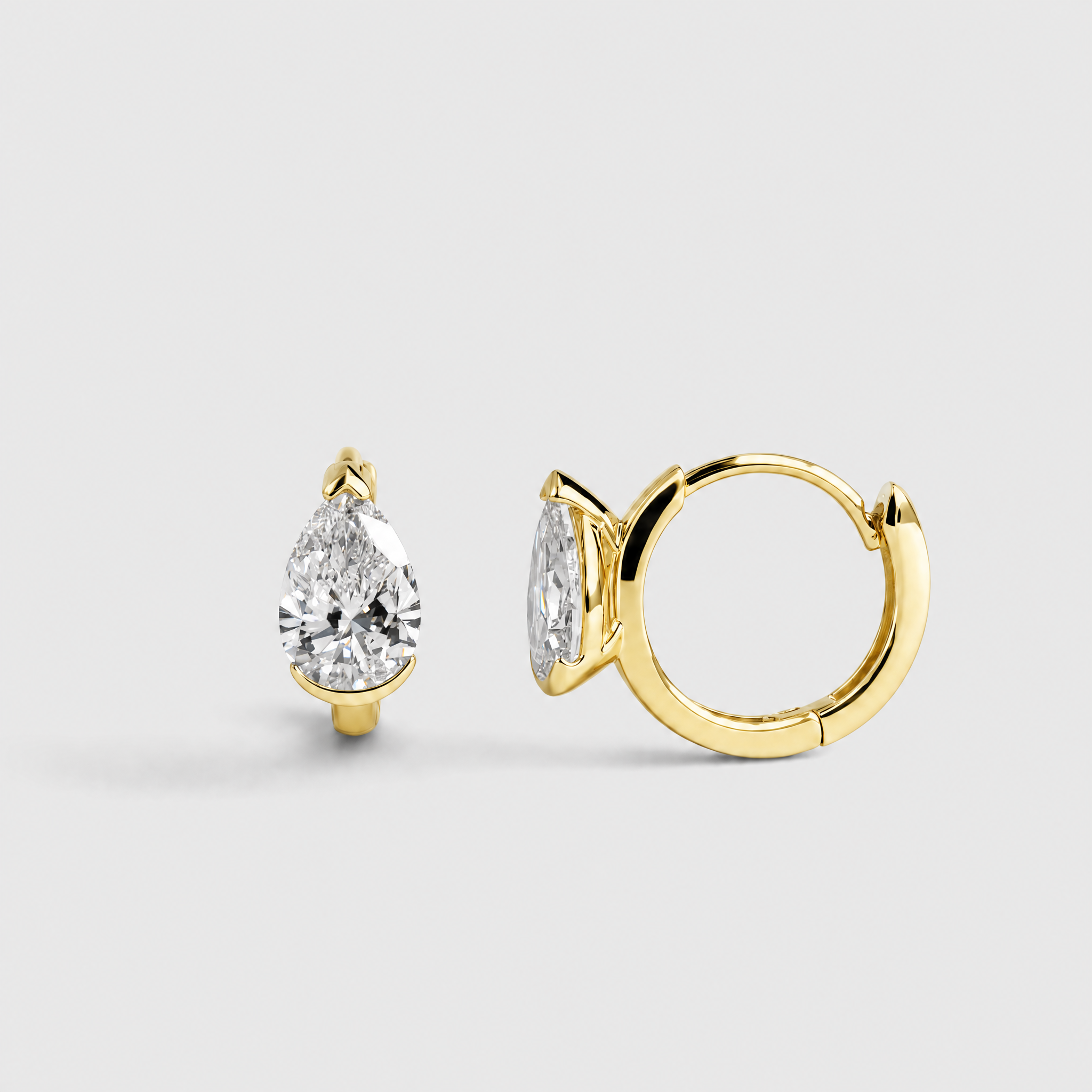 Rear profile view of pear-shaped hoop earrings in yellow gold showing the hoop closures and stone settings.