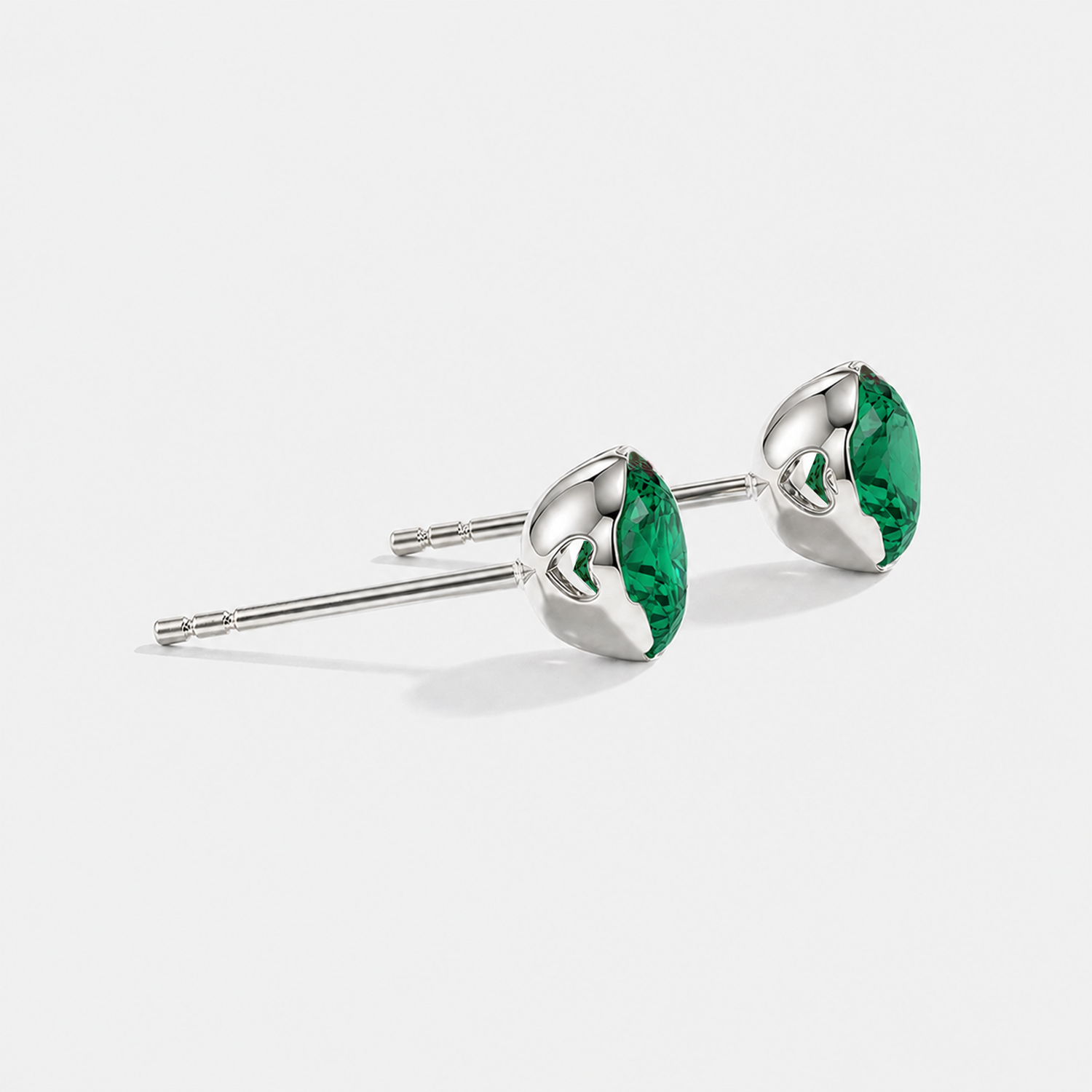 Side view of round lab-grown emerald stud earrings in white gold.