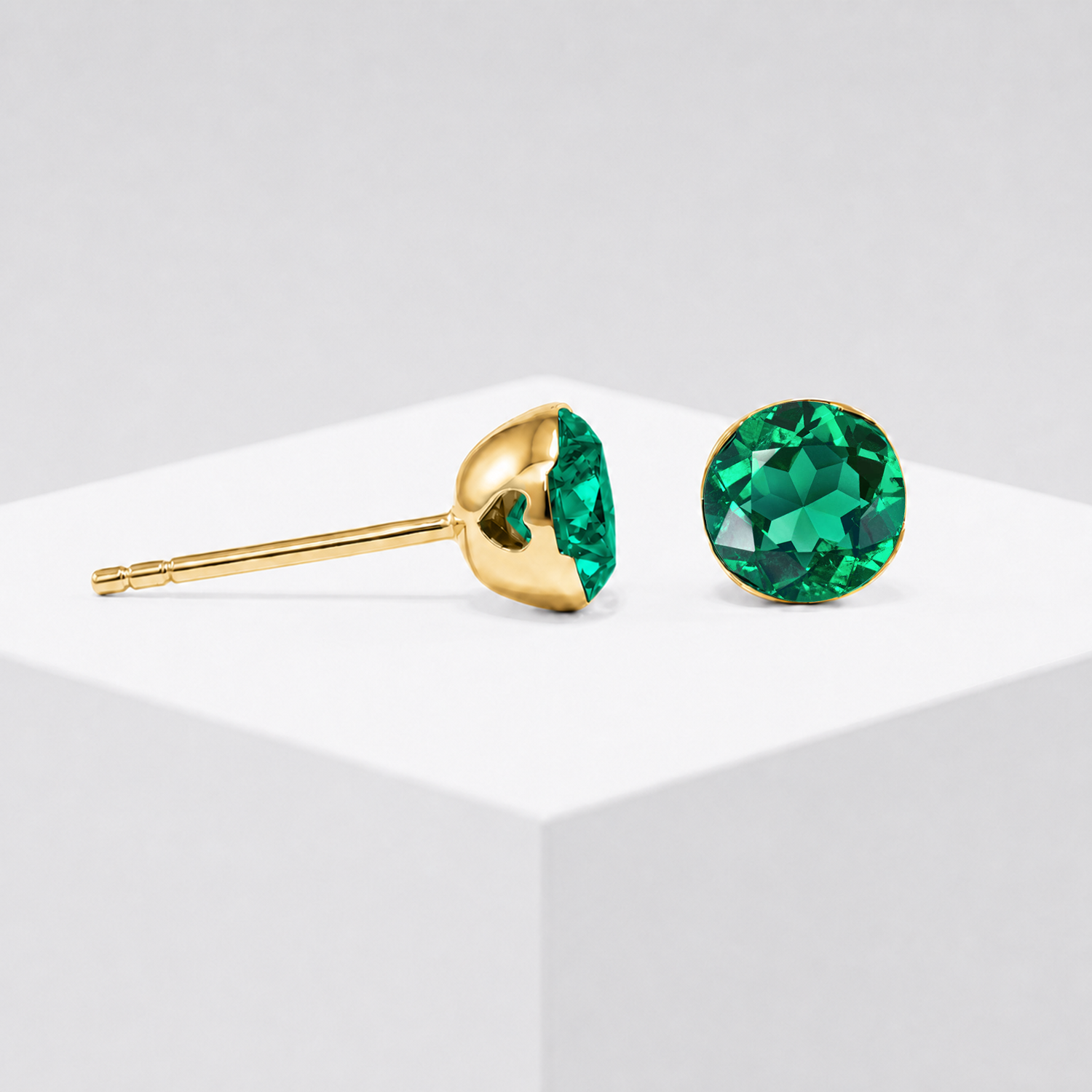 Close-up view of the round lab-grown emerald stud earring setting in yellow gold.