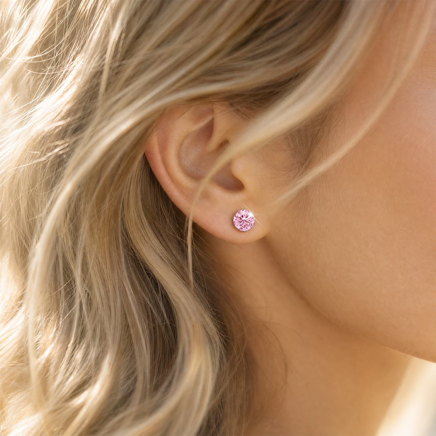 Close-up of a round pink lab-grown diamond stud earring worn on the ear.