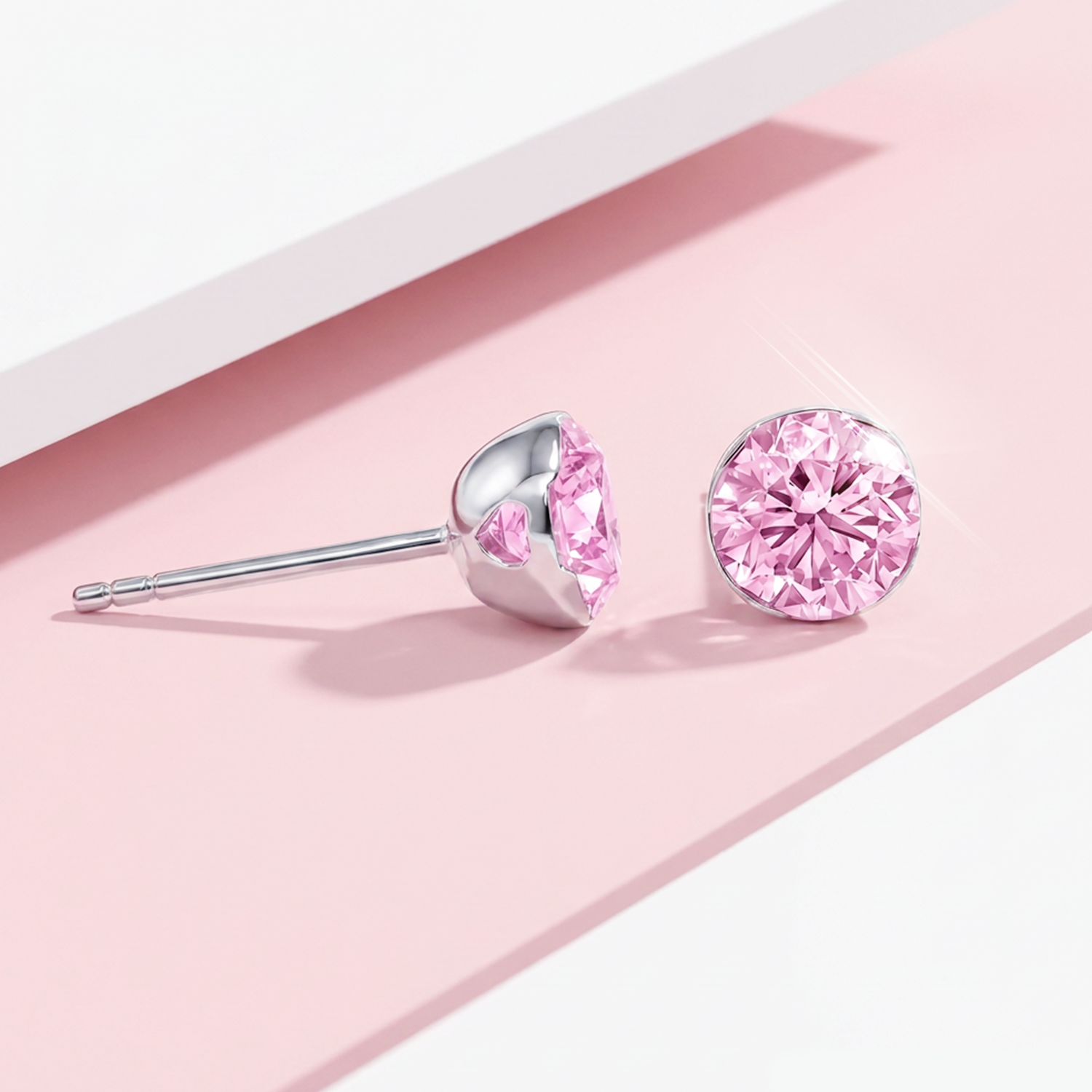 Round pink lab-grown diamond stud earrings shown from the front and side on a pink display surface.