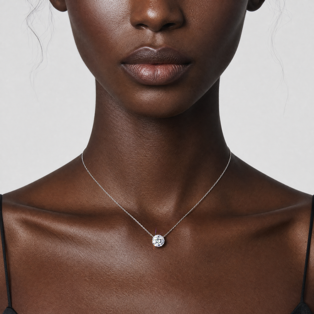 Model wearing a white gold round diamond solitaire necklace.