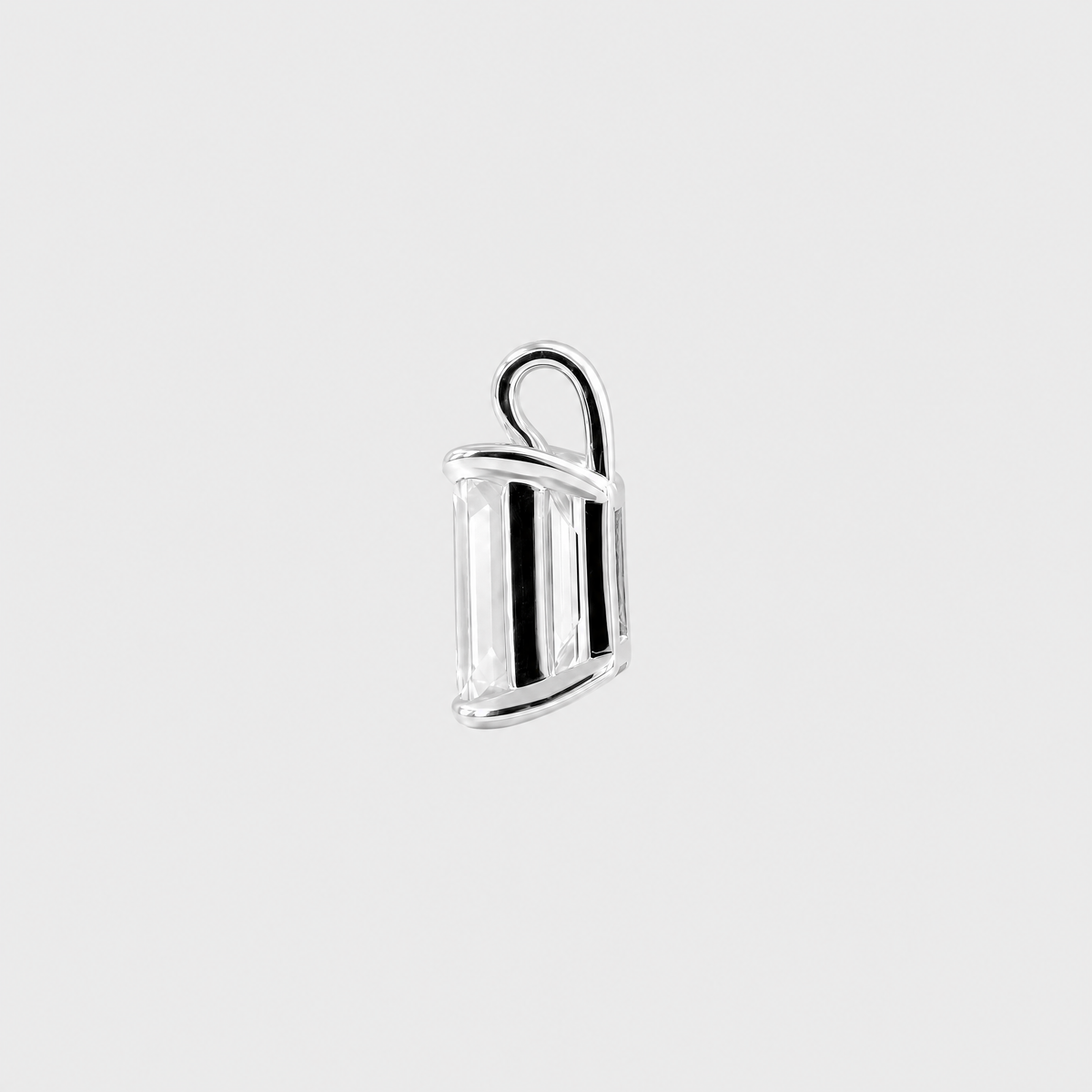Side view of an emerald-cut solitaire pendant in white metal showing the open setting and bail.