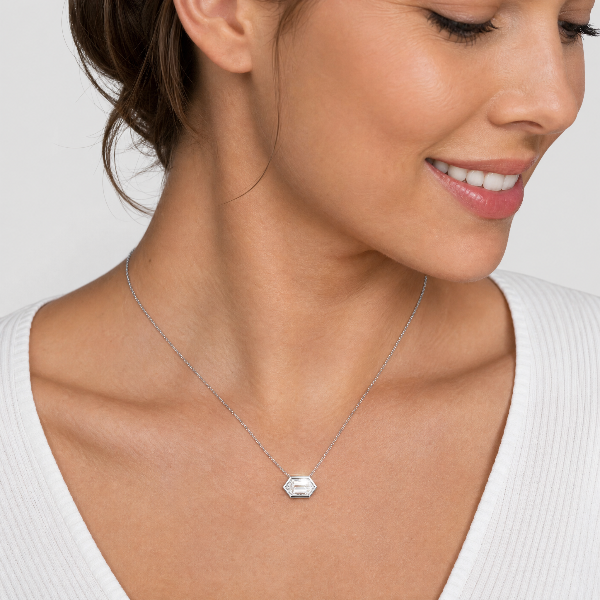 Model wearing an elongated hexagon-cut diamond pendant in white gold on a fine chain.