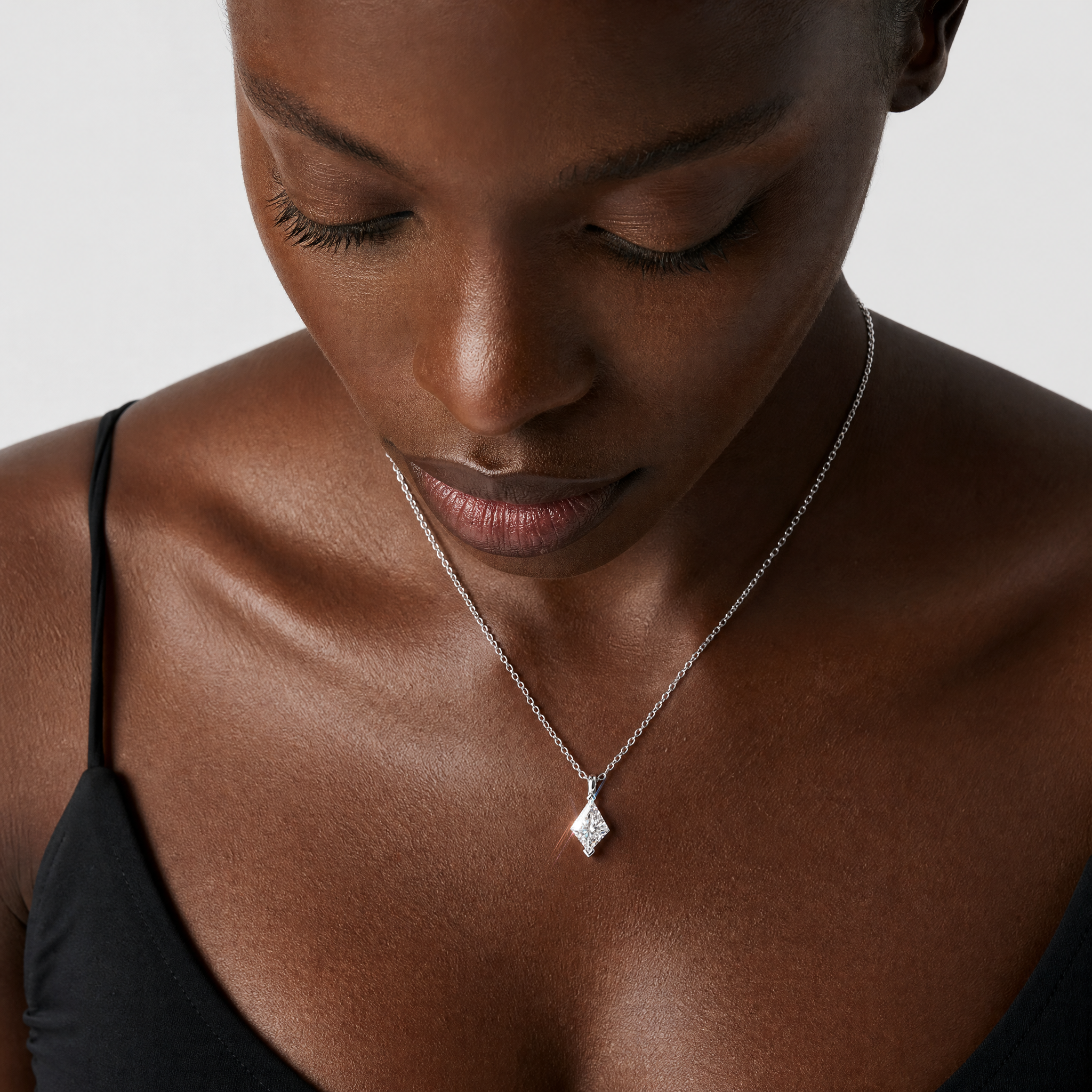 White-gold kite-cut pendant worn on a fine chain in a close-up neck view.