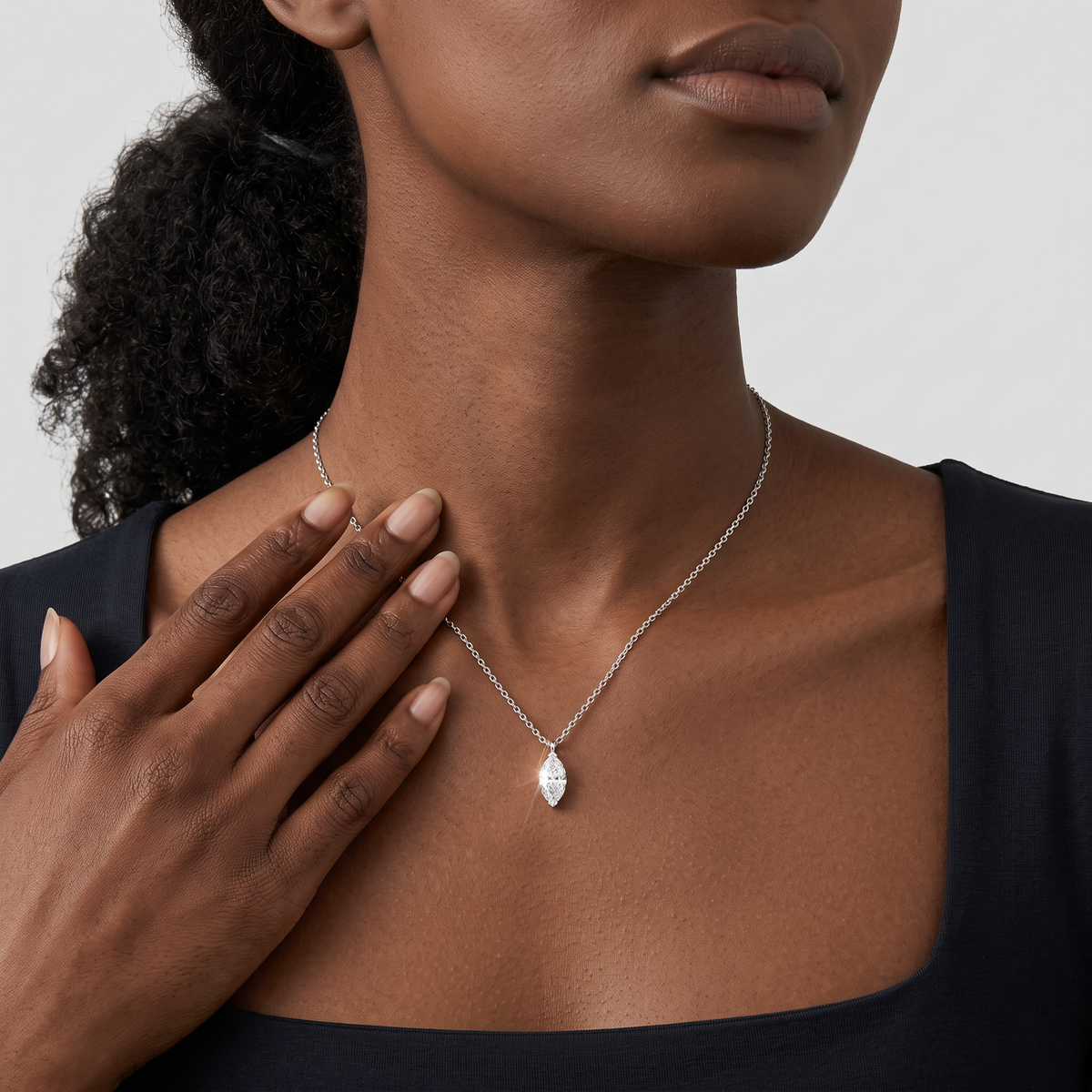 White-gold marquise-cut pendant worn on a fine chain in a close-up neck view.