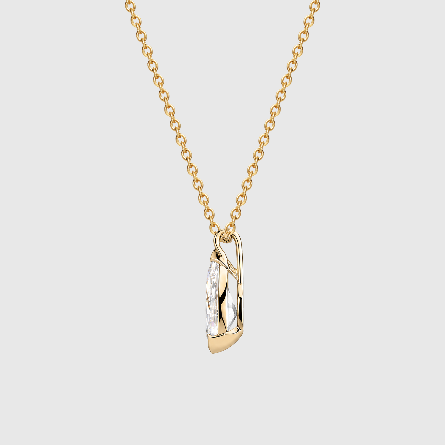 Side view of a pear-cut diamond pendant in yellow gold showing the half-bezel profile and bail.