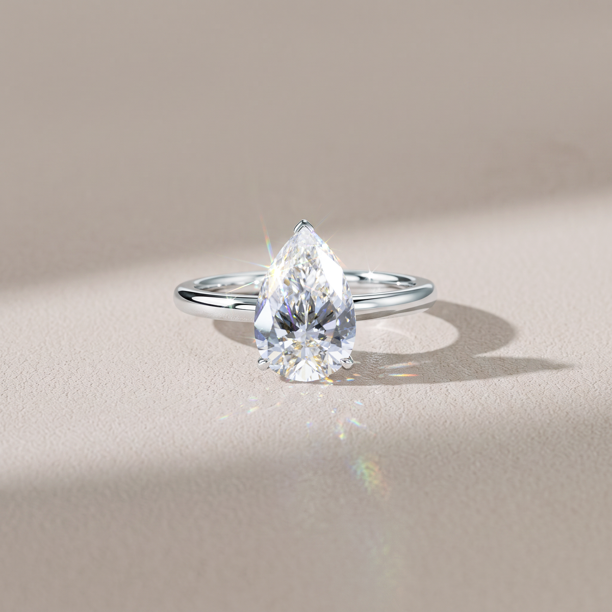 Pear-shaped lab-grown diamond solitaire engagement ring in white gold styled on hand.
