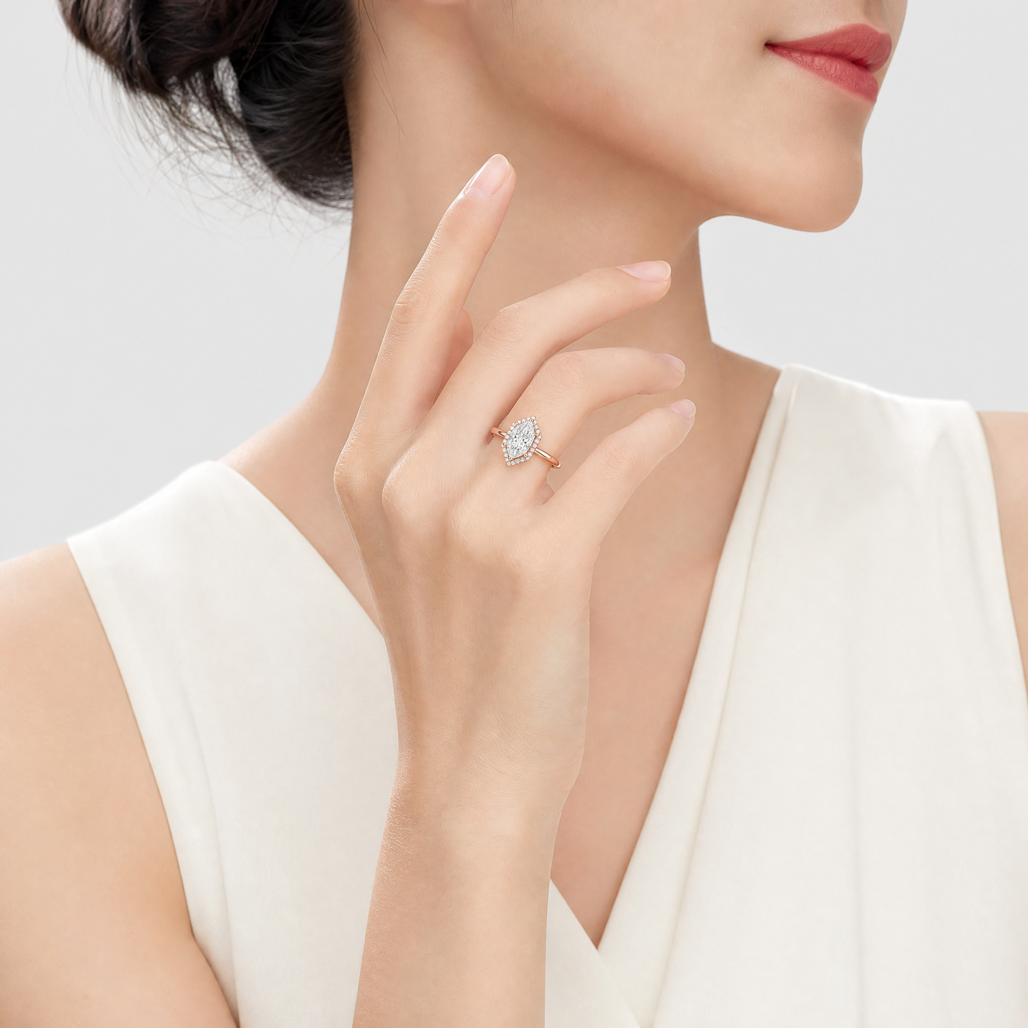 Close-up of a hand wearing a halo hexagon diamond ring with a plain background