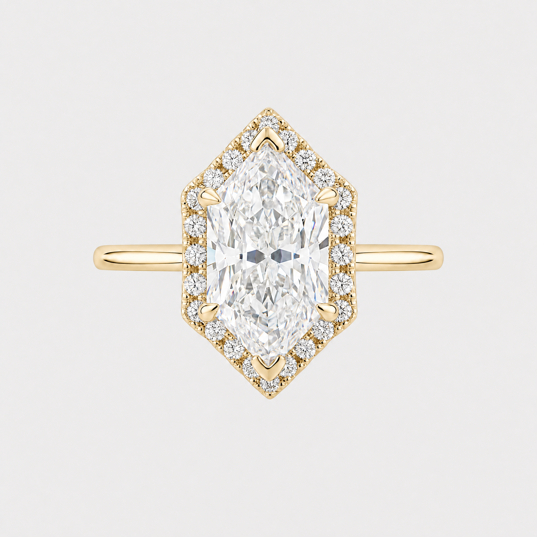 A yellow gold ring featuring a dutch- hexagon cut diamond center stone surrounded by a diamond halo, set on a gold band against a light gray background.