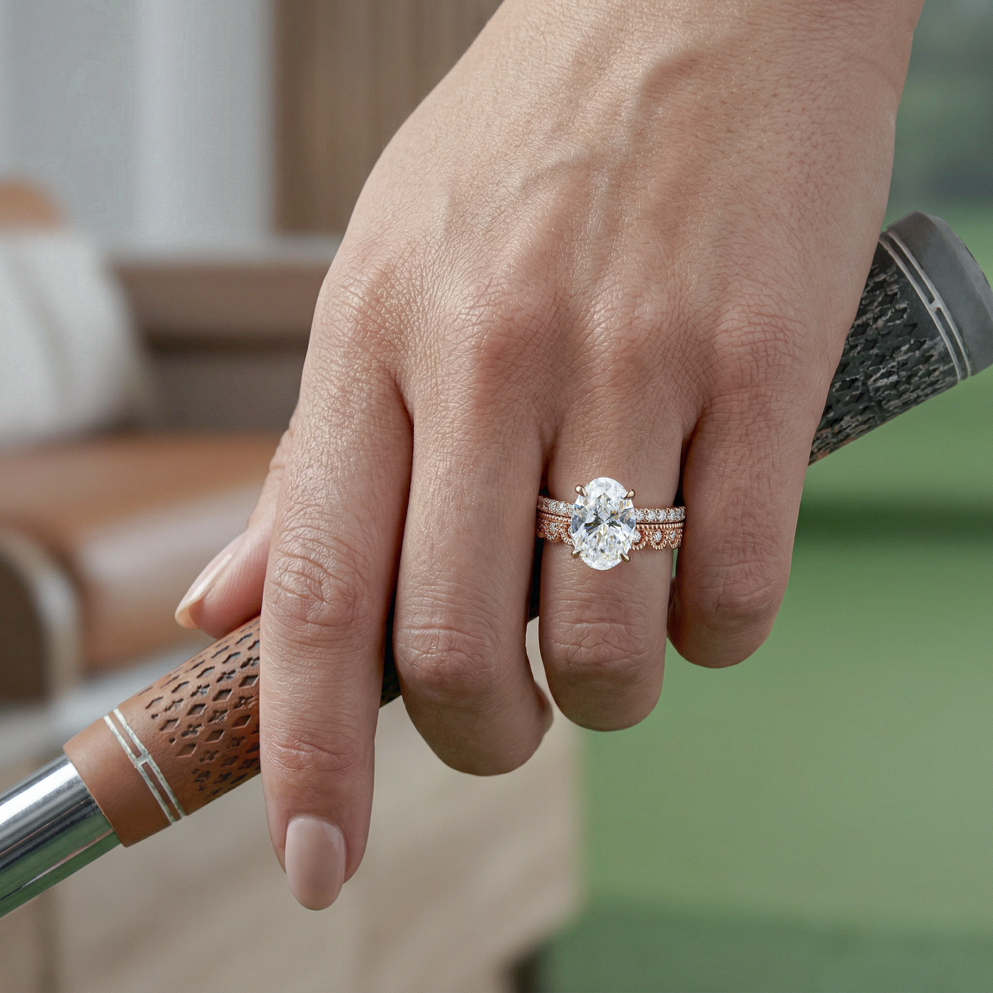 Hand holding a golf club with a oval diamond ring on the ring finger