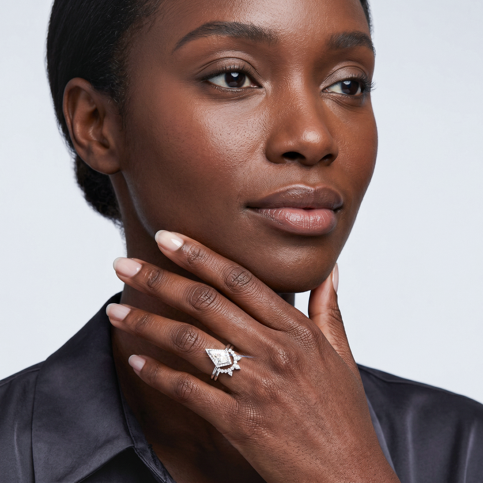 Woman wearing halo kite shape diamond ring set 2pcs on her finger against a plain background