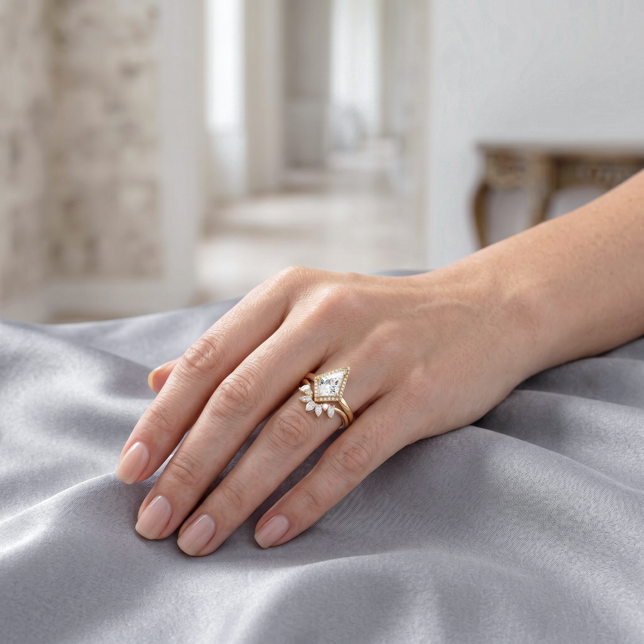 Hand wearing golden kite cut diamond ring set on a soft fabric surface