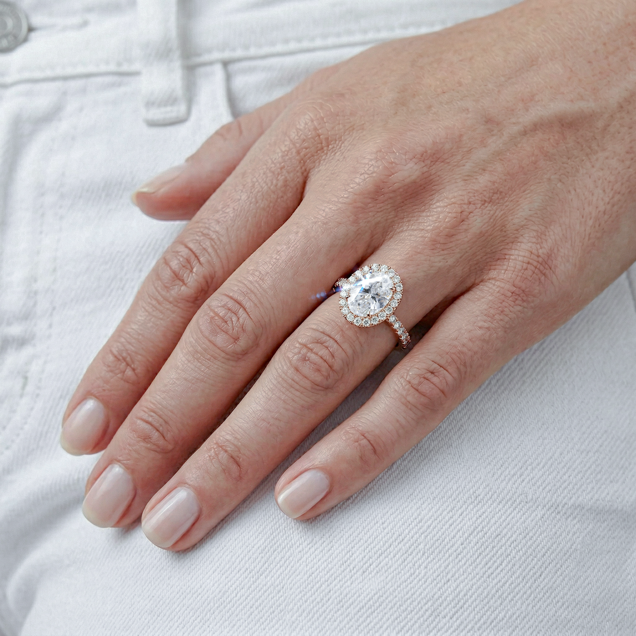 Close-up of a hand wearing a diamond ring on a white background