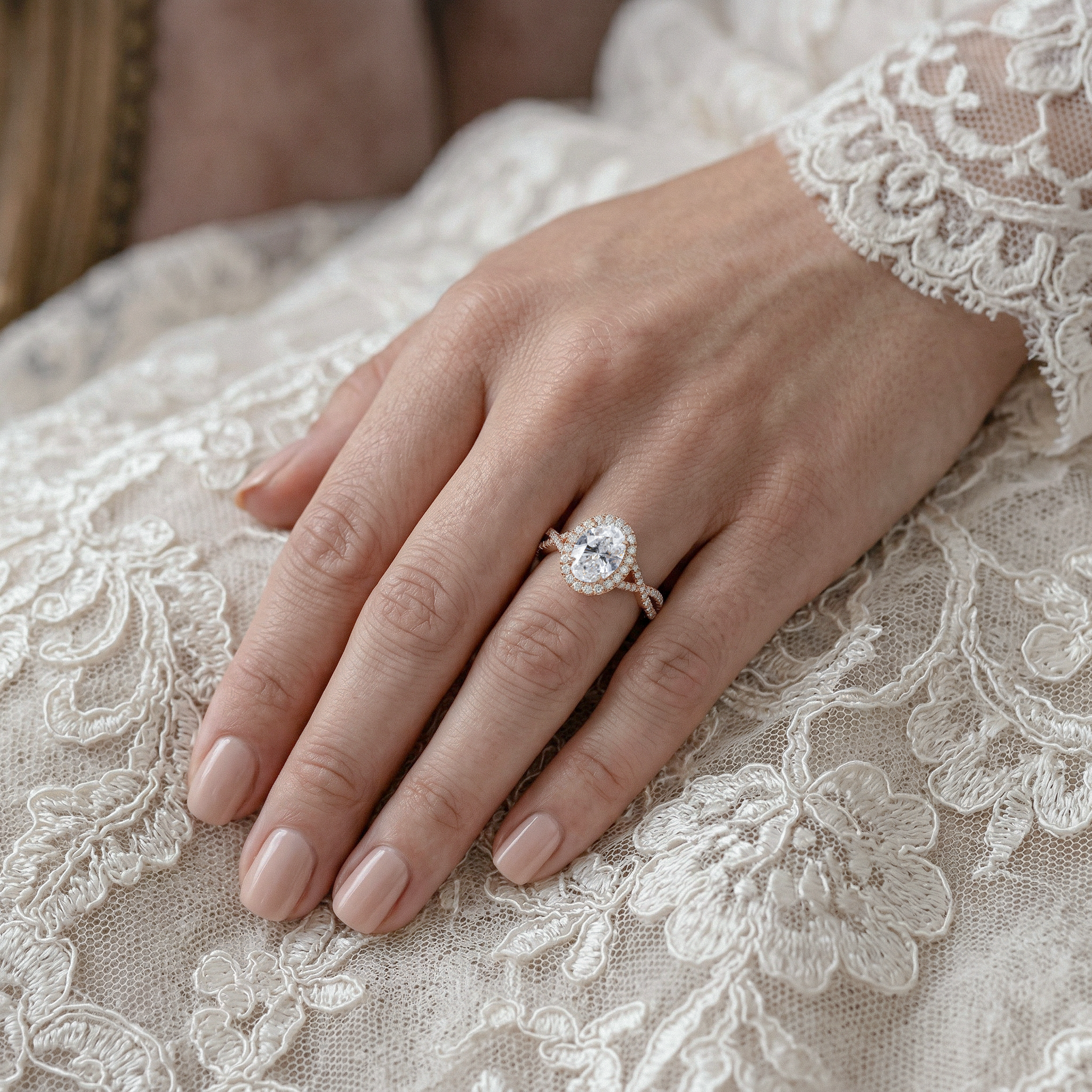 Hand wearing a twisted oval diamond ring on lace fabric
