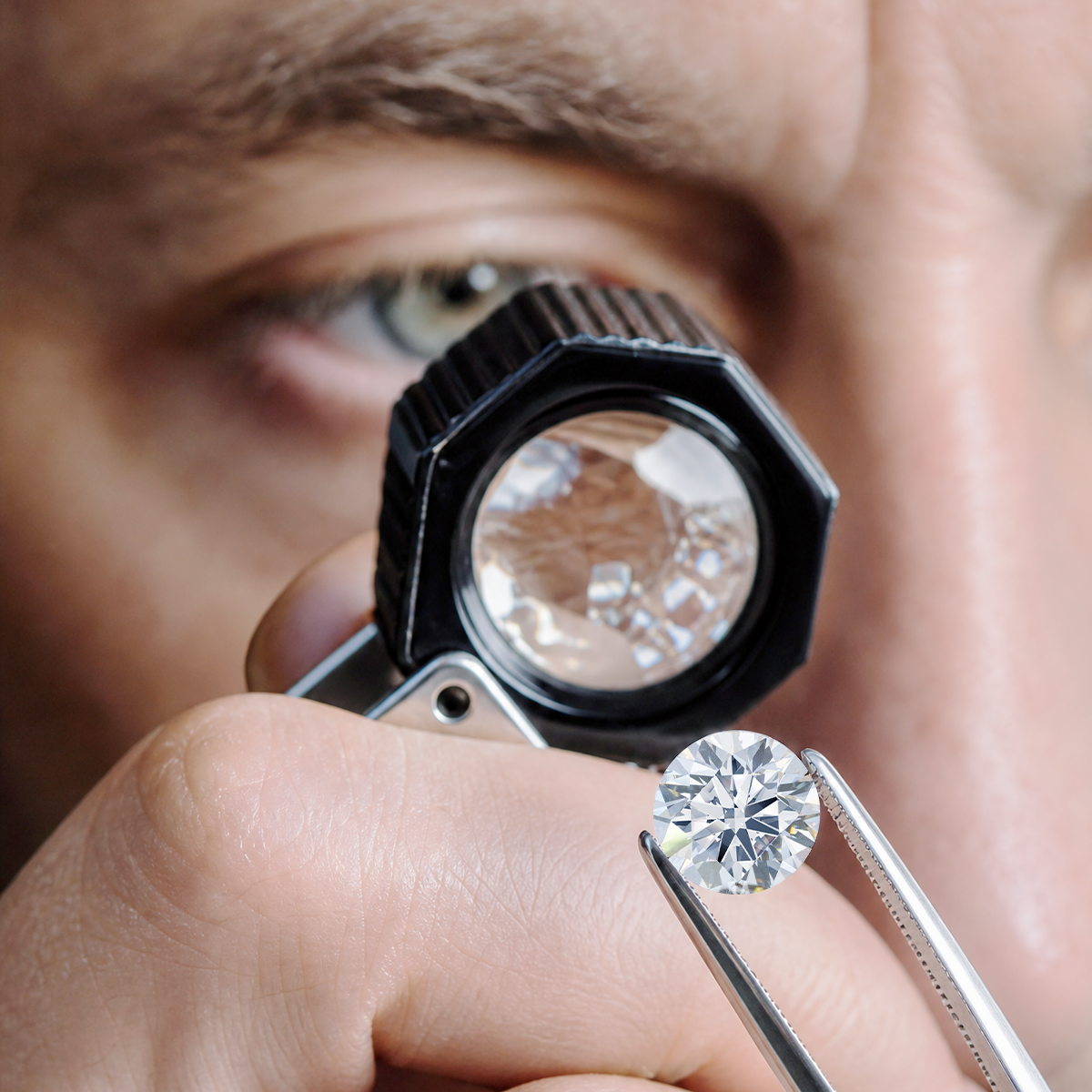 Person examining a diamond with a magnifying glass