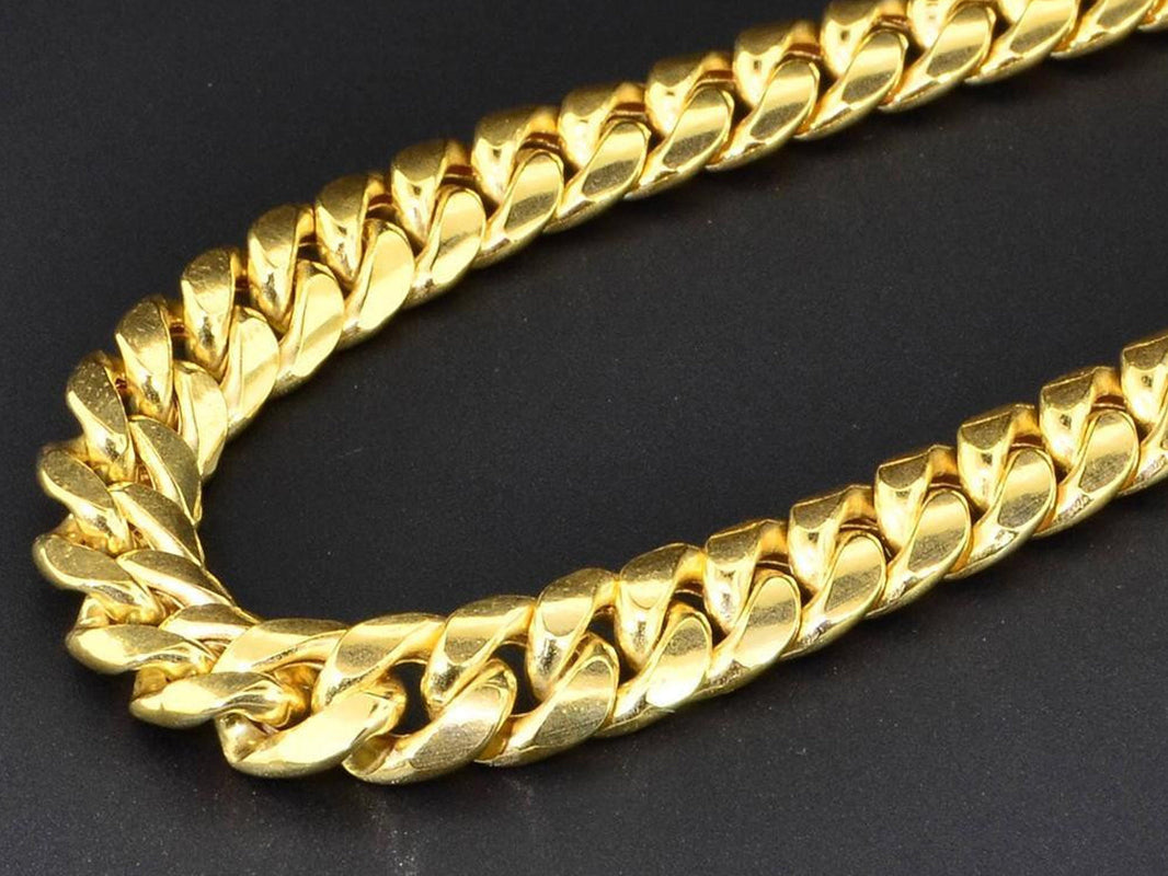 Close-up of a thick hollow Cuban link gold necklace on a black background
