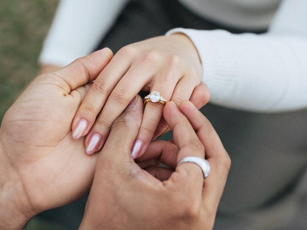 An intimate moment of a person placing an engagement ring on their partner's finger