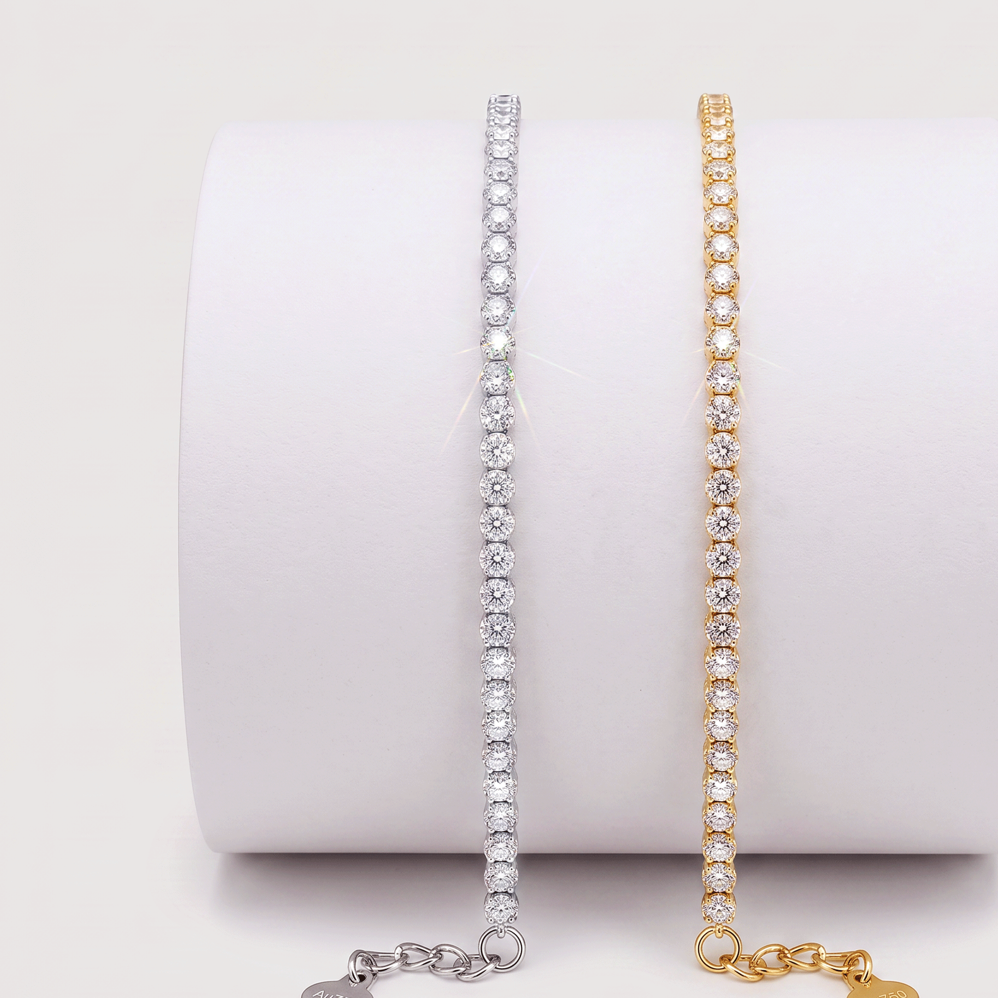 White and yellow gold lab-grown diamond tennis bracelets displayed side by side on a white jewelry stand.