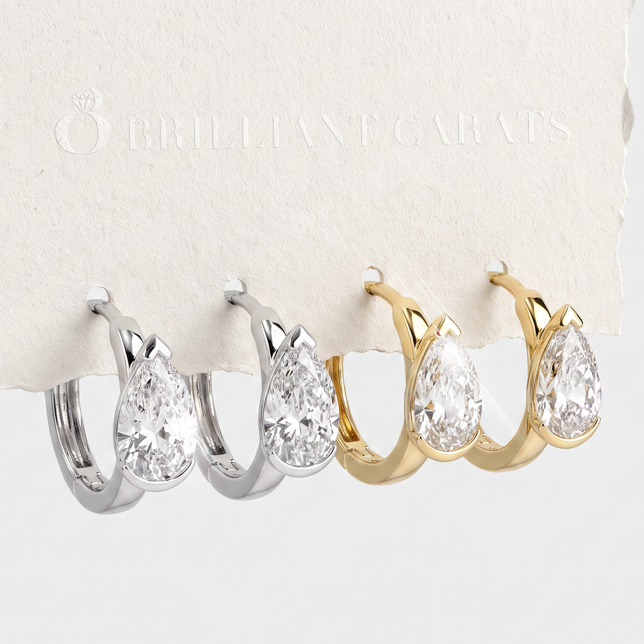 White- and yellow-gold pear-shaped hoop earrings displayed beside a Brilliant Carats card.