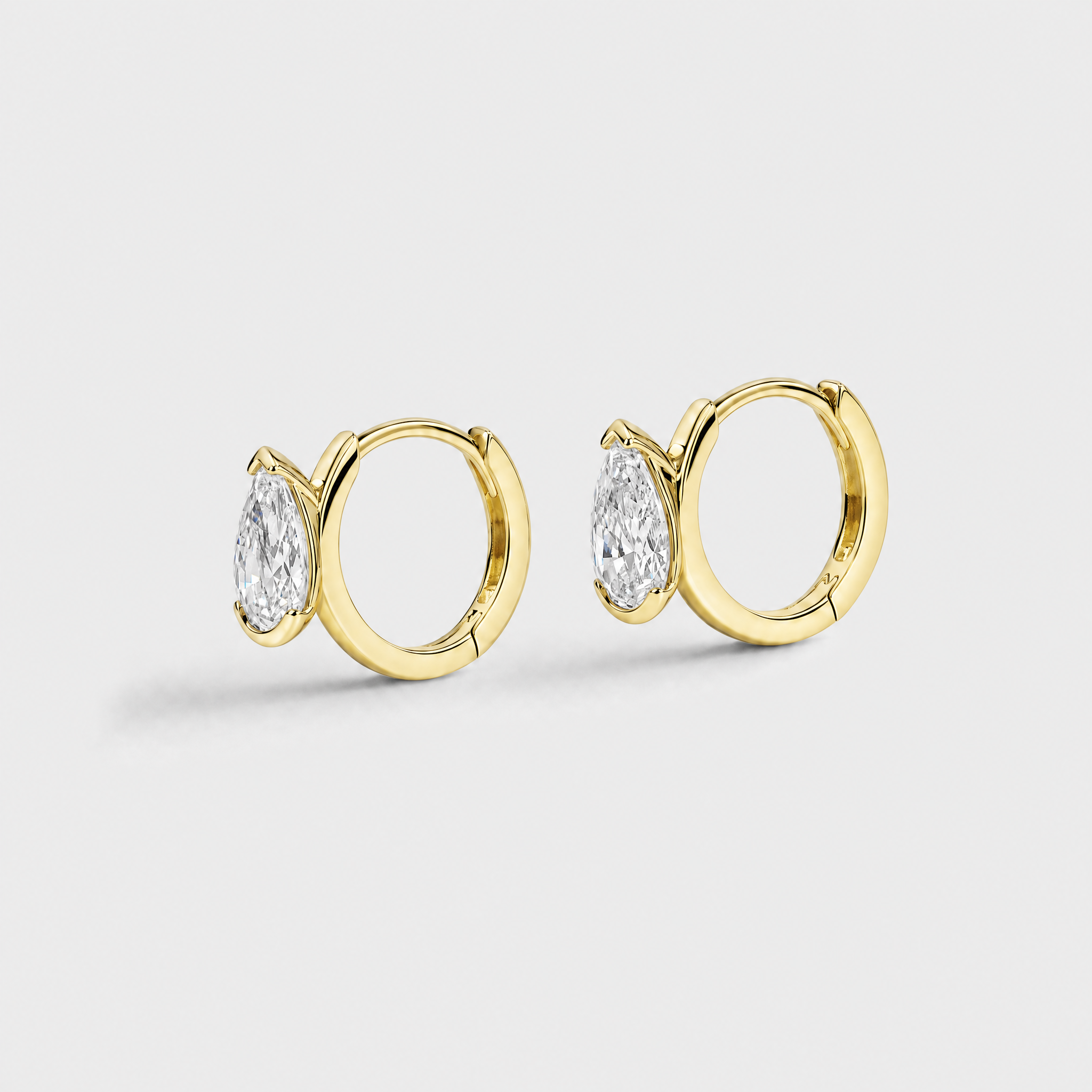 Side view of pear-shaped hoop earrings in yellow gold showing the hinged hoops and stone settings.