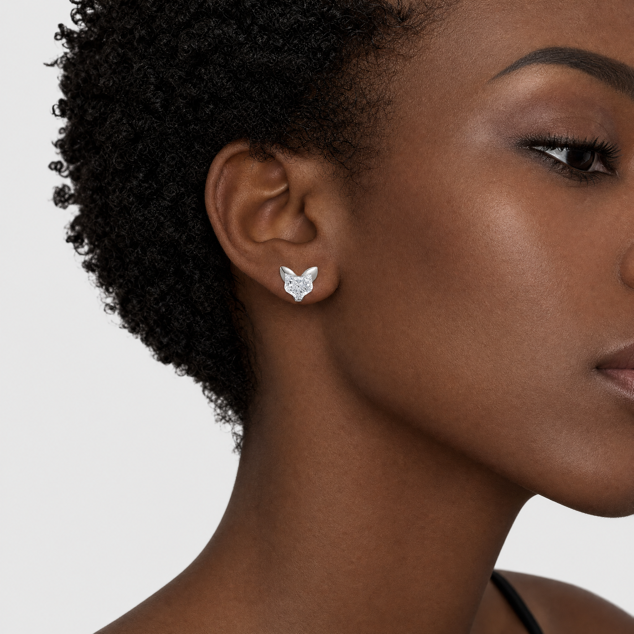 Close-up of a woman wearing cat shaped earrings on a neutral background