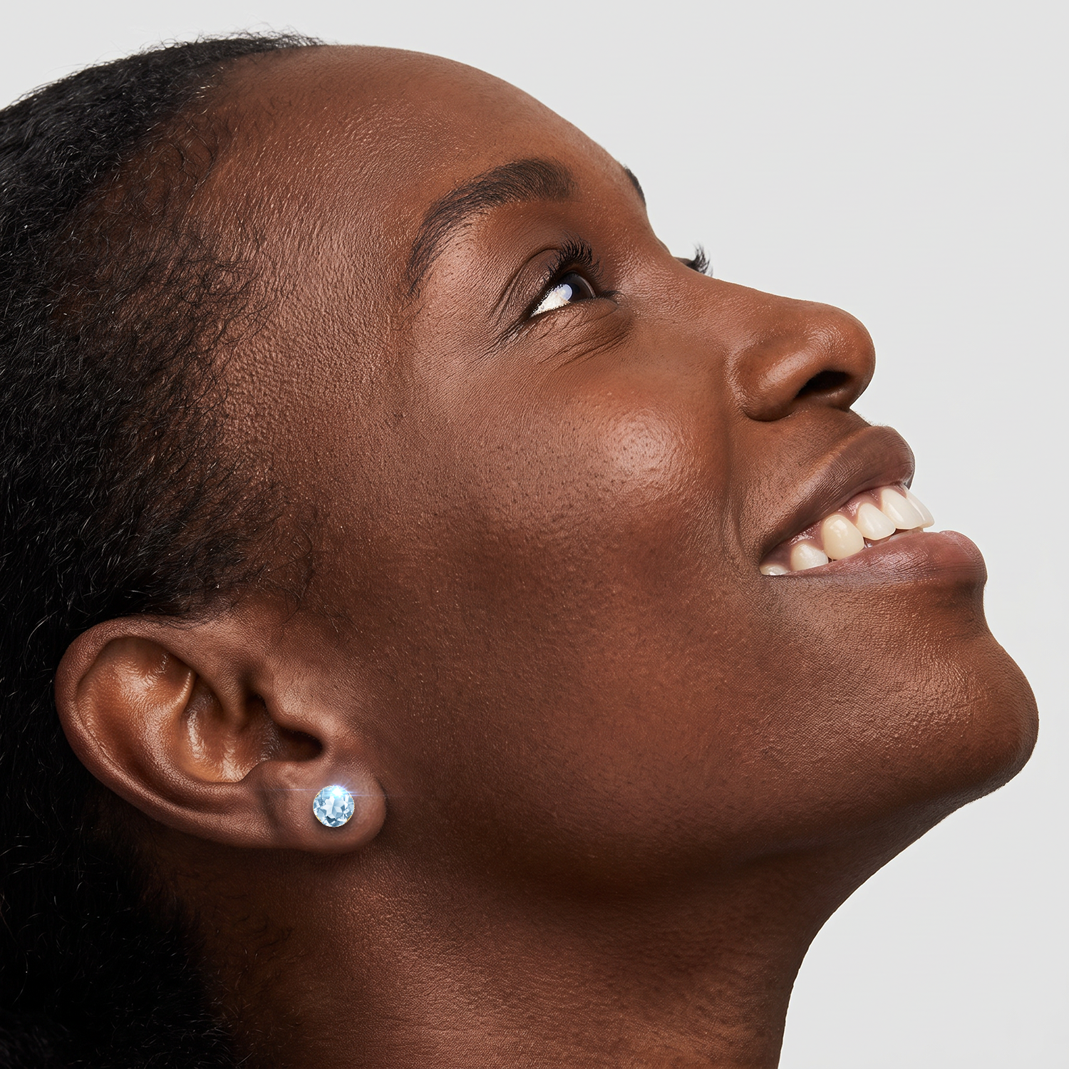Round lab-grown aquamarine stud earring in yellow gold worn by a model.