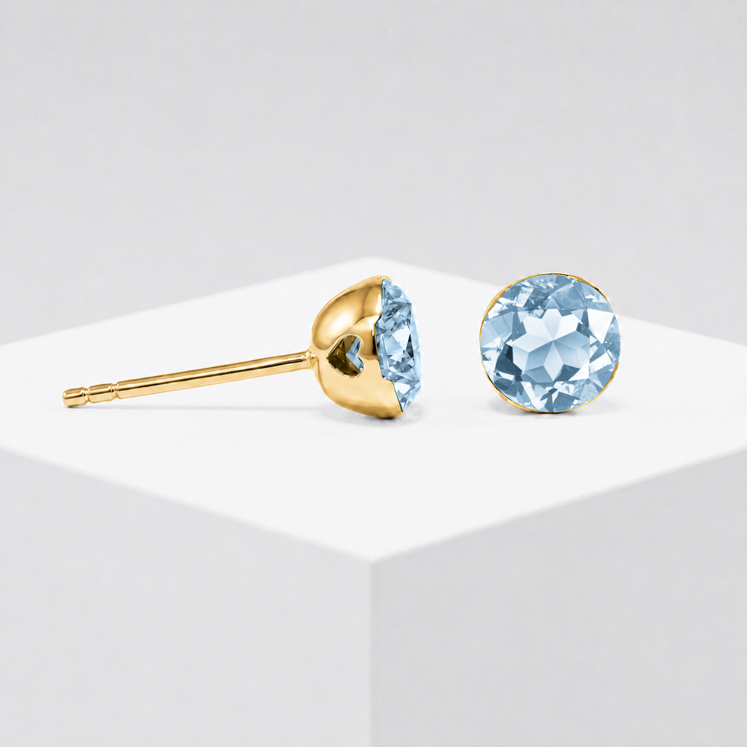 Round lab-grown aquamarine stud earrings shown from the front and side in yellow gold.