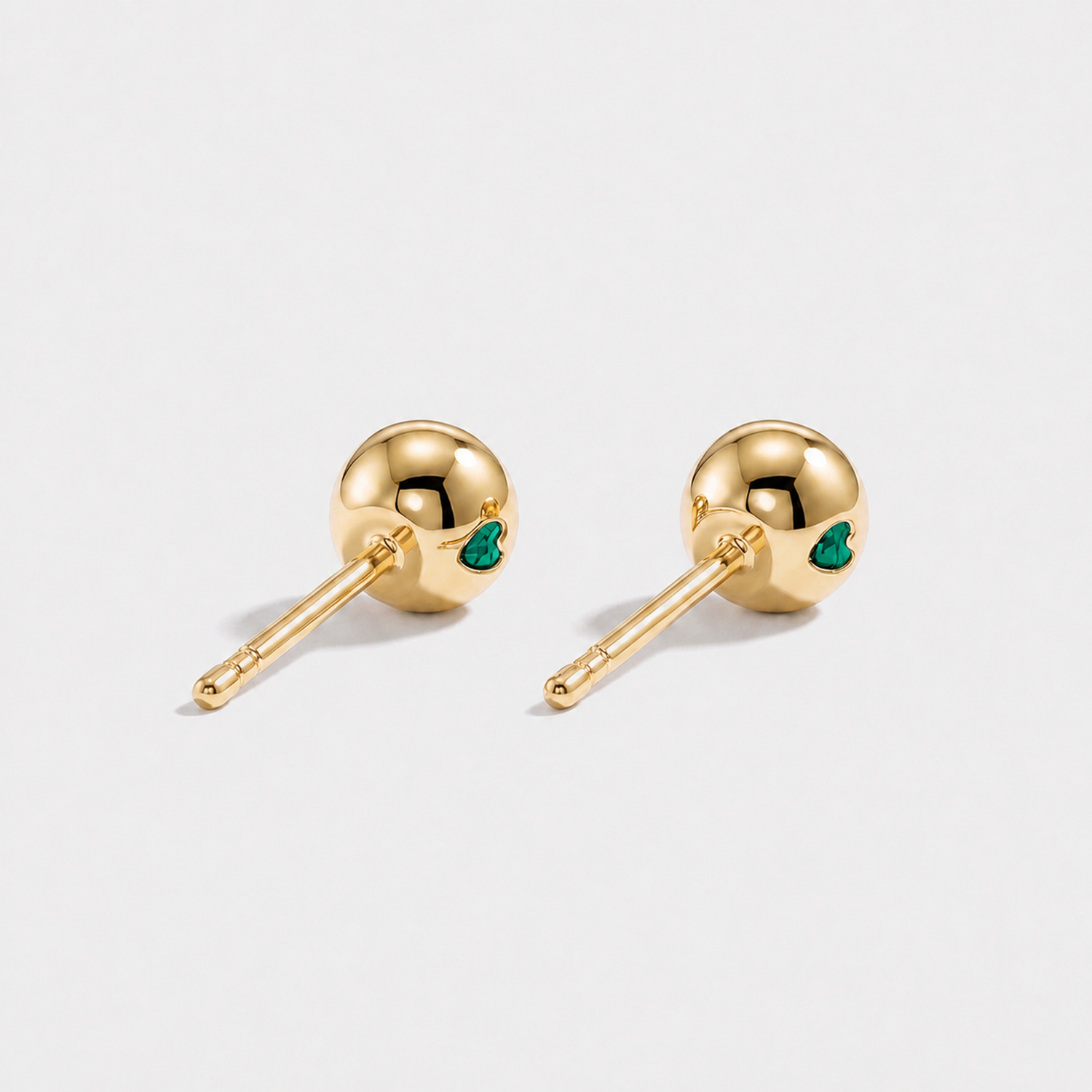 Back view of round lab-grown emerald stud earrings in yellow gold.