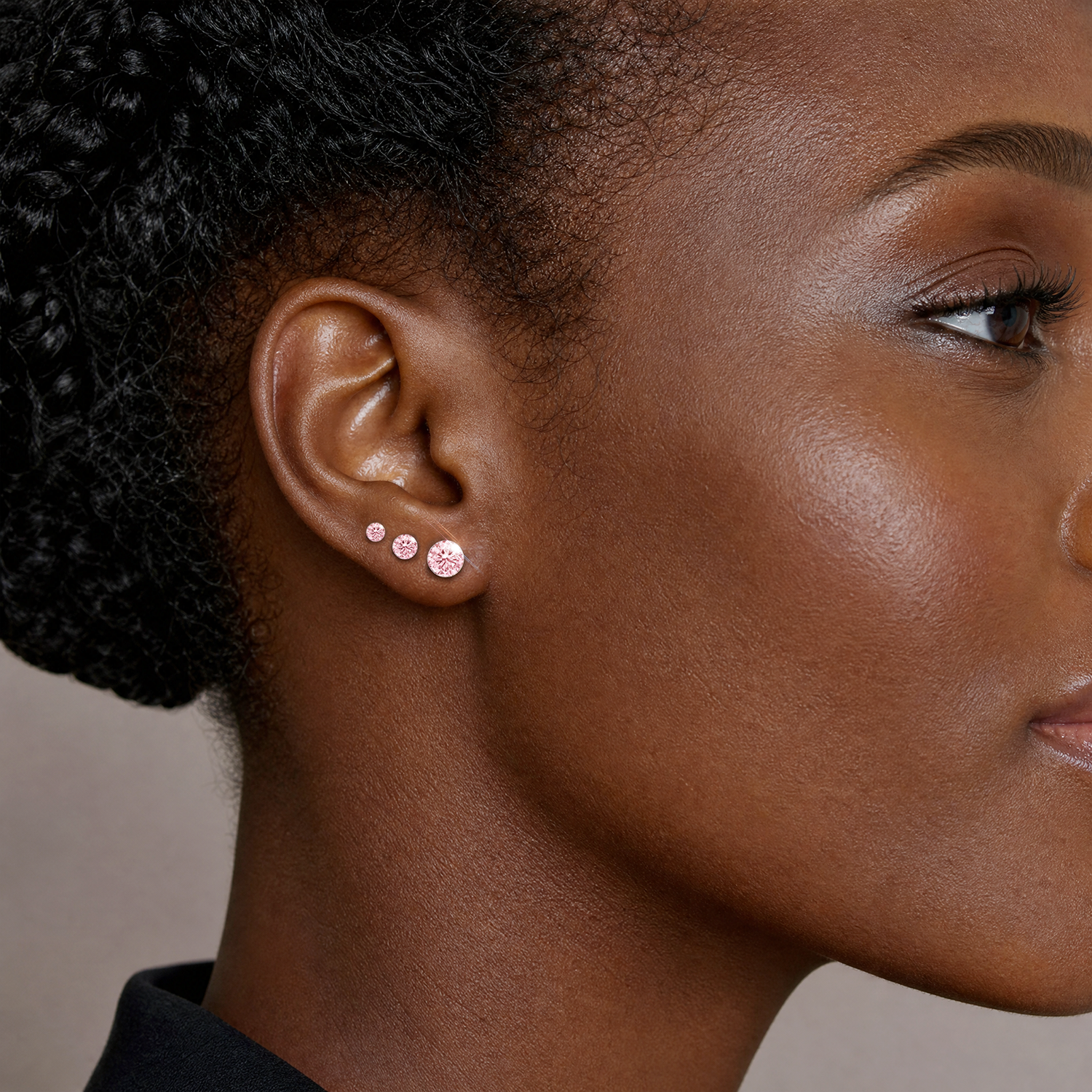 Three round pink lab-grown diamond stud sizes shown worn along the earlobe.