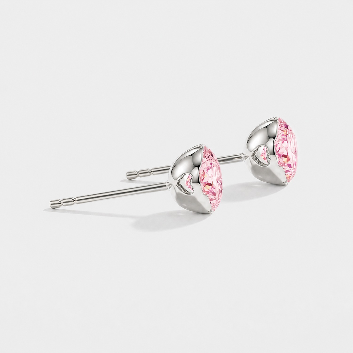 Side view of round pink lab-grown diamond stud earrings showing heart-shaped openings in the white gold settings.
