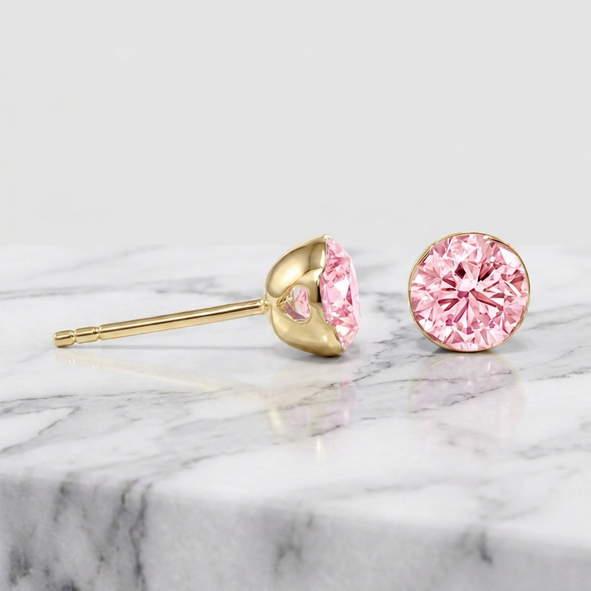 Round pink lab-grown diamond stud earrings shown from the front and side in yellow gold.