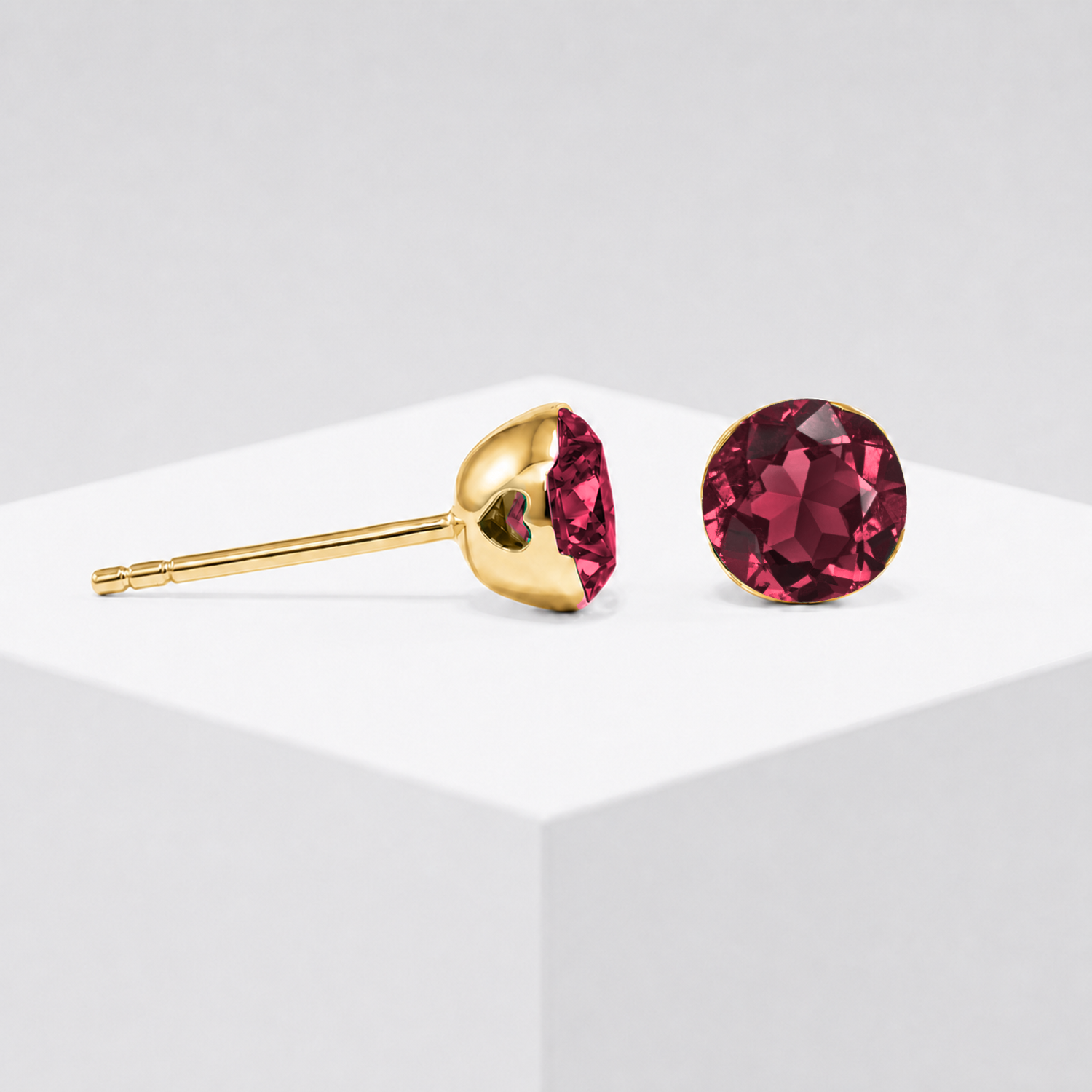 Close-up view of the round lab-grown ruby stud earring setting in yellow gold.