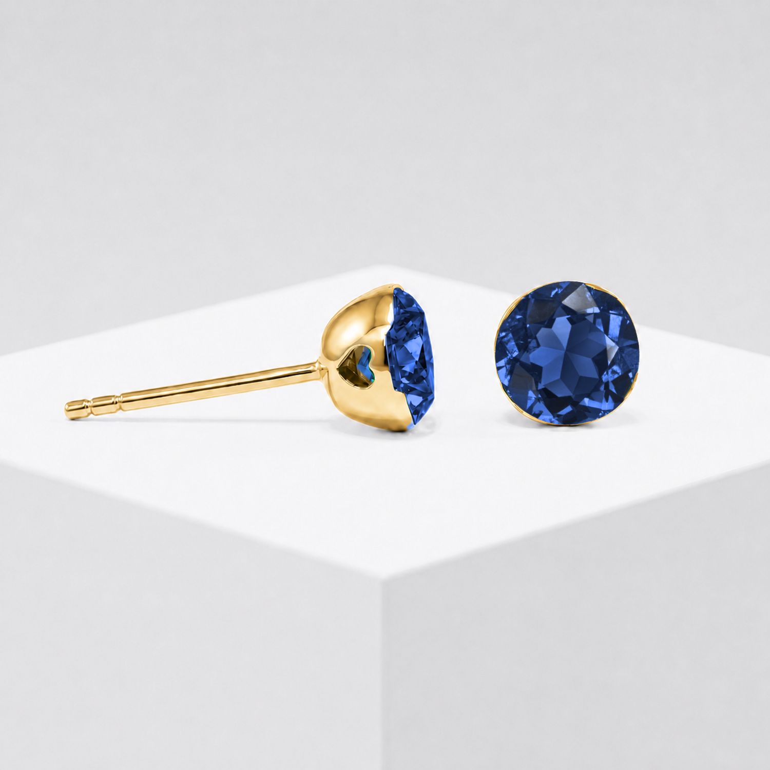Round lab-grown sapphire stud earrings shown from the front and side in yellow gold.