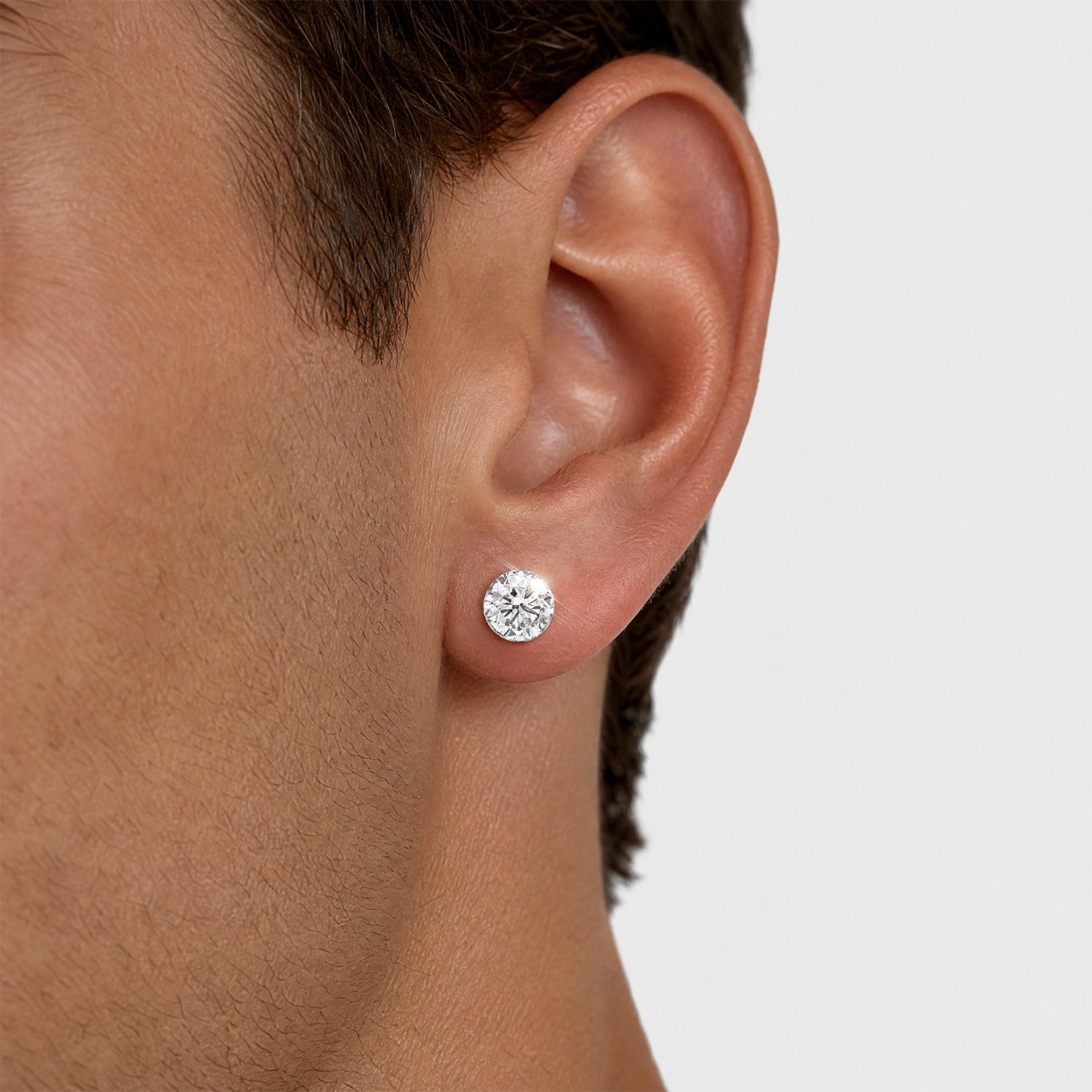 White metal round stone stud earrings shown close-up on the ear