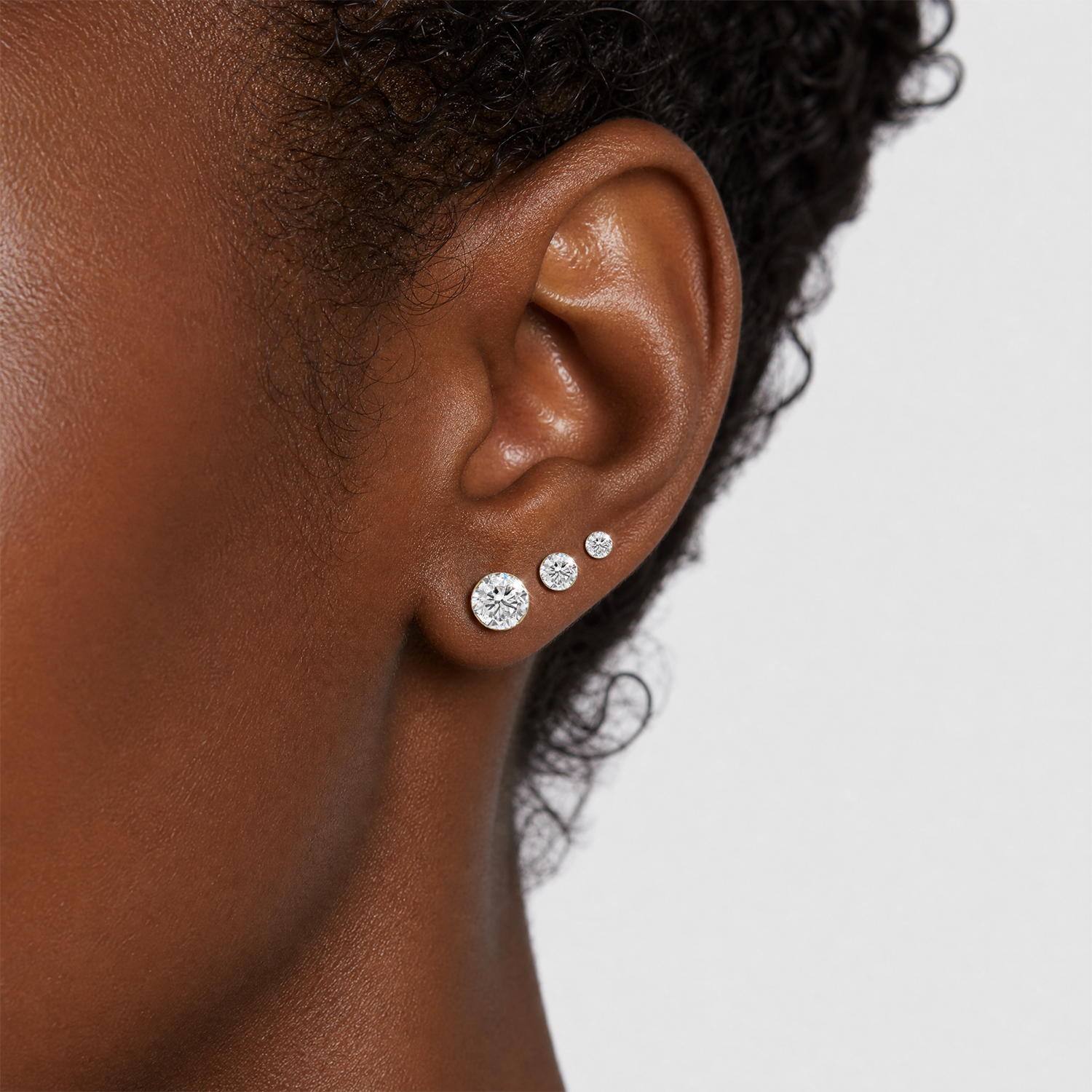 Yellow gold round stone stud earrings, close-up on the ear