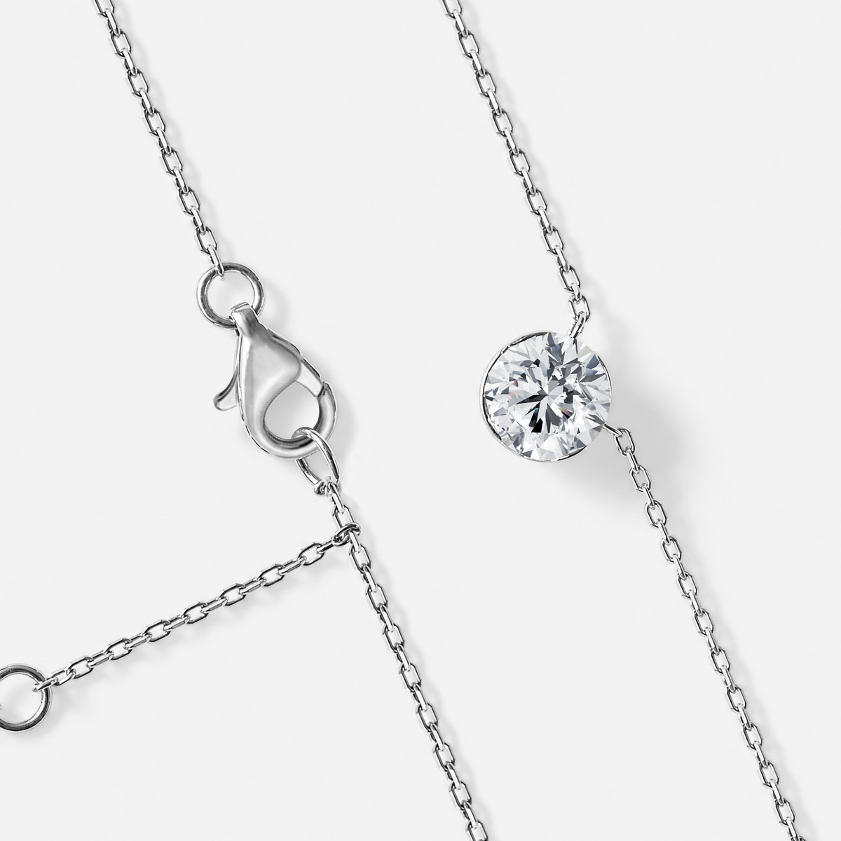 White gold round diamond solitaire necklace with chain and clasp detail.