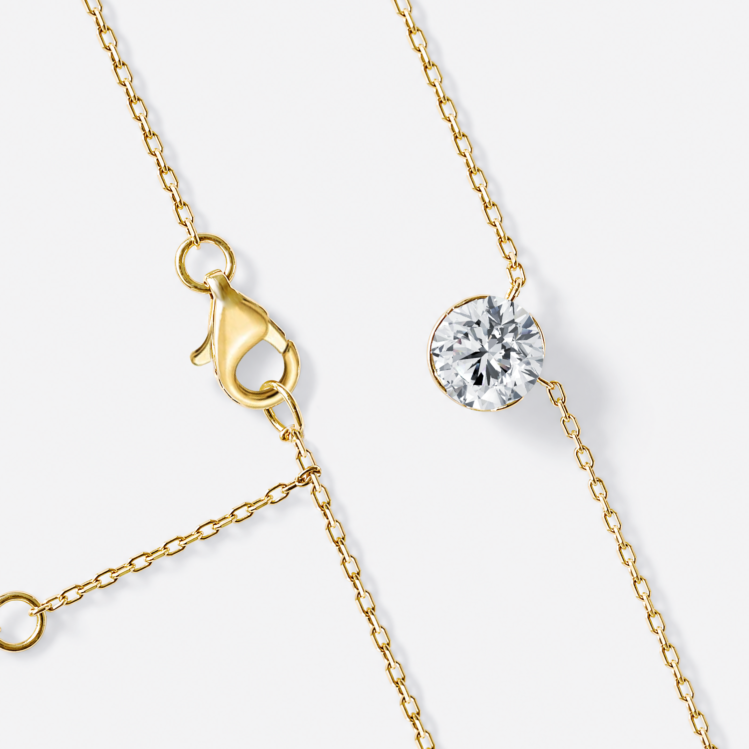 Yellow gold round diamond solitaire necklace with chain and clasp detail.