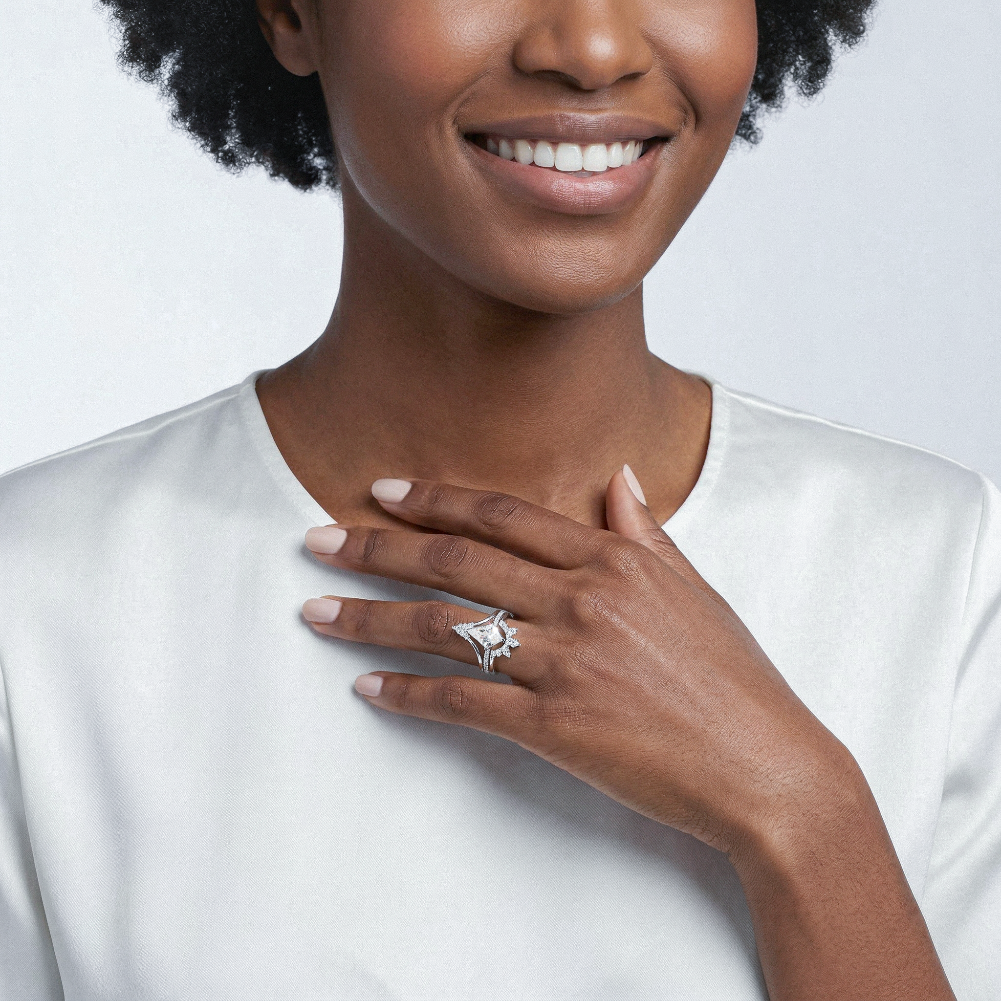 Woman wearing Kite  diamond ring set on a plain background