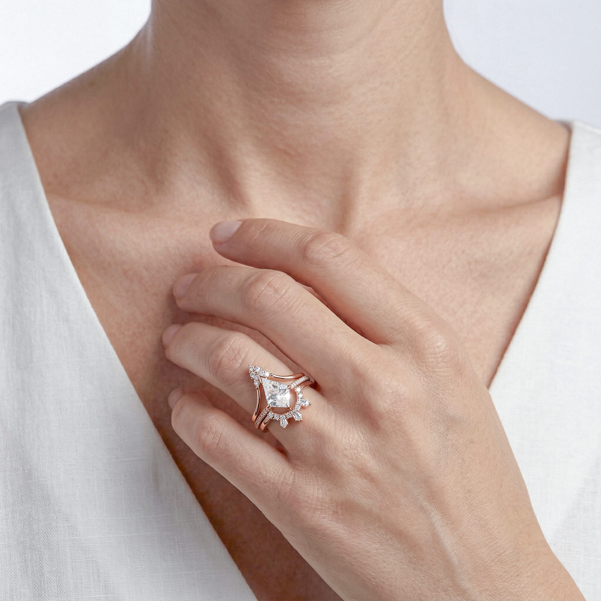 Close-up of a hand wearing Kite  diamond ring set on a white background