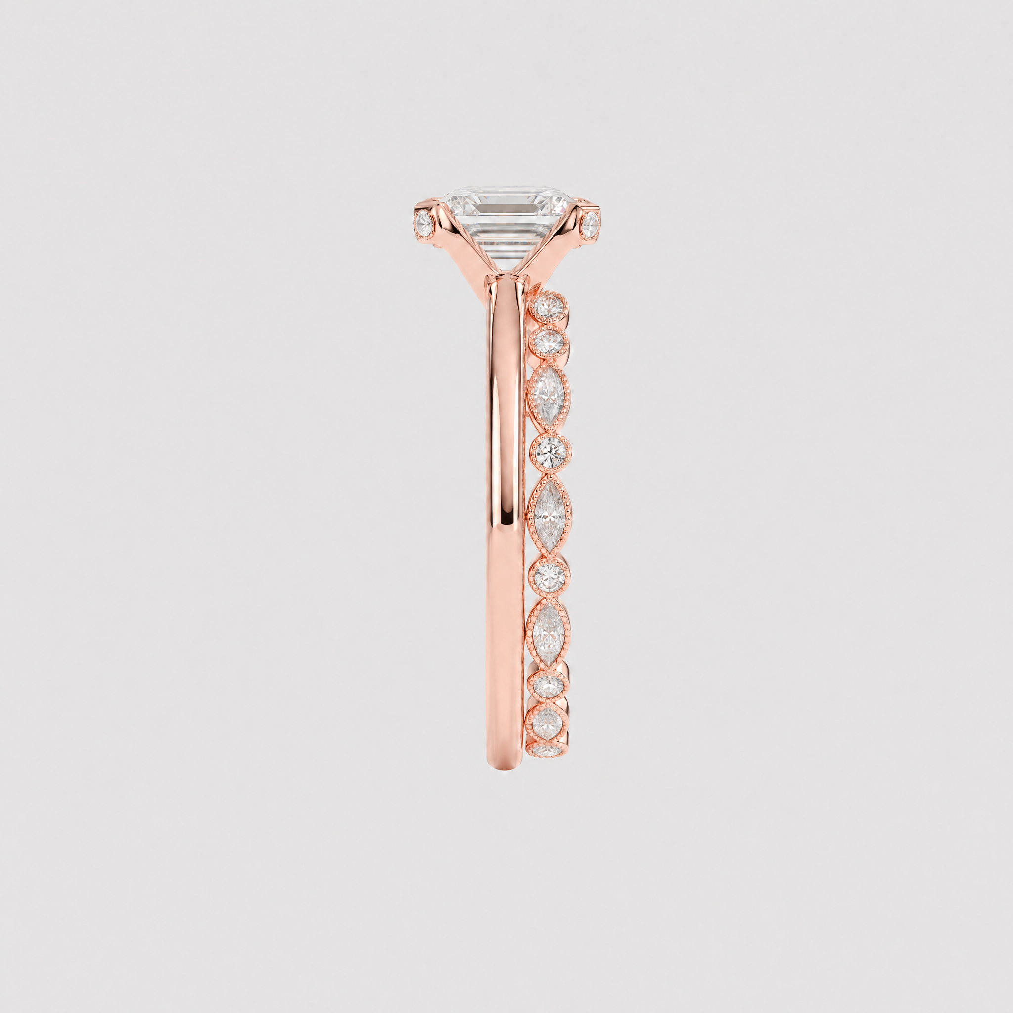 Side view of a rose gold bridal set showing the emerald-cut center setting and marquise-and-round stone band.