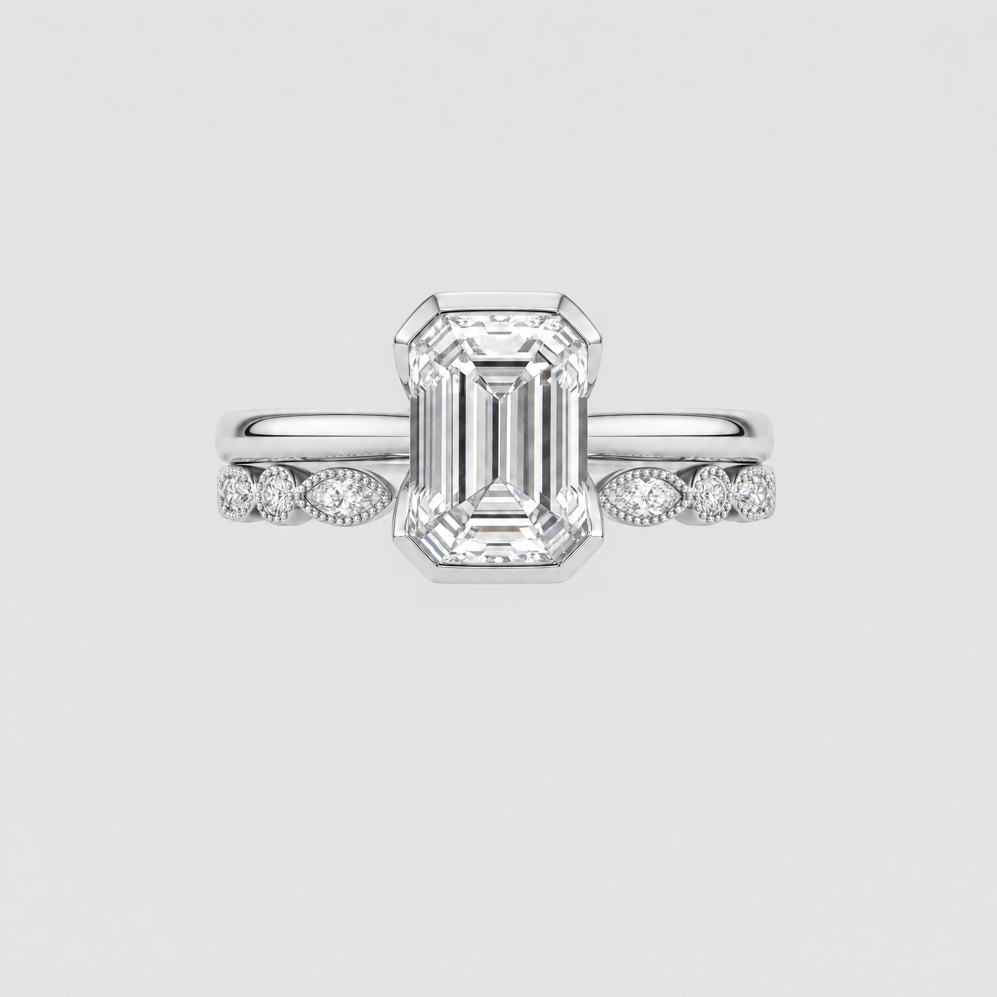 Front view of an emerald-cut two-ring bridal set in white metal with a marquise-and-round stone band.